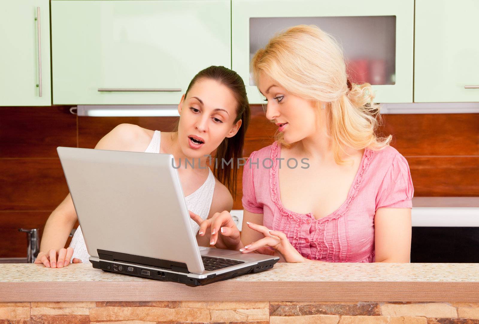 Two young women with a laptop in the kitchen