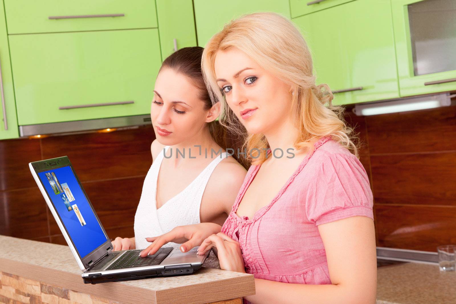 Two young women with a laptop in the kitchen
