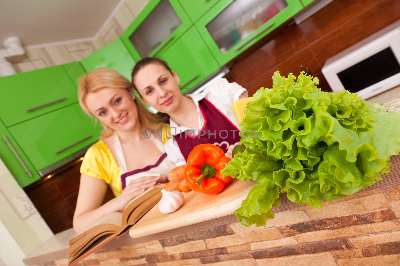 two young housewives are preparing a salad of fresh vegetables and fruits