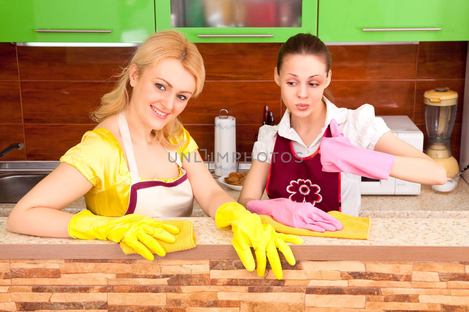 Two young attractive women clean the kitchen