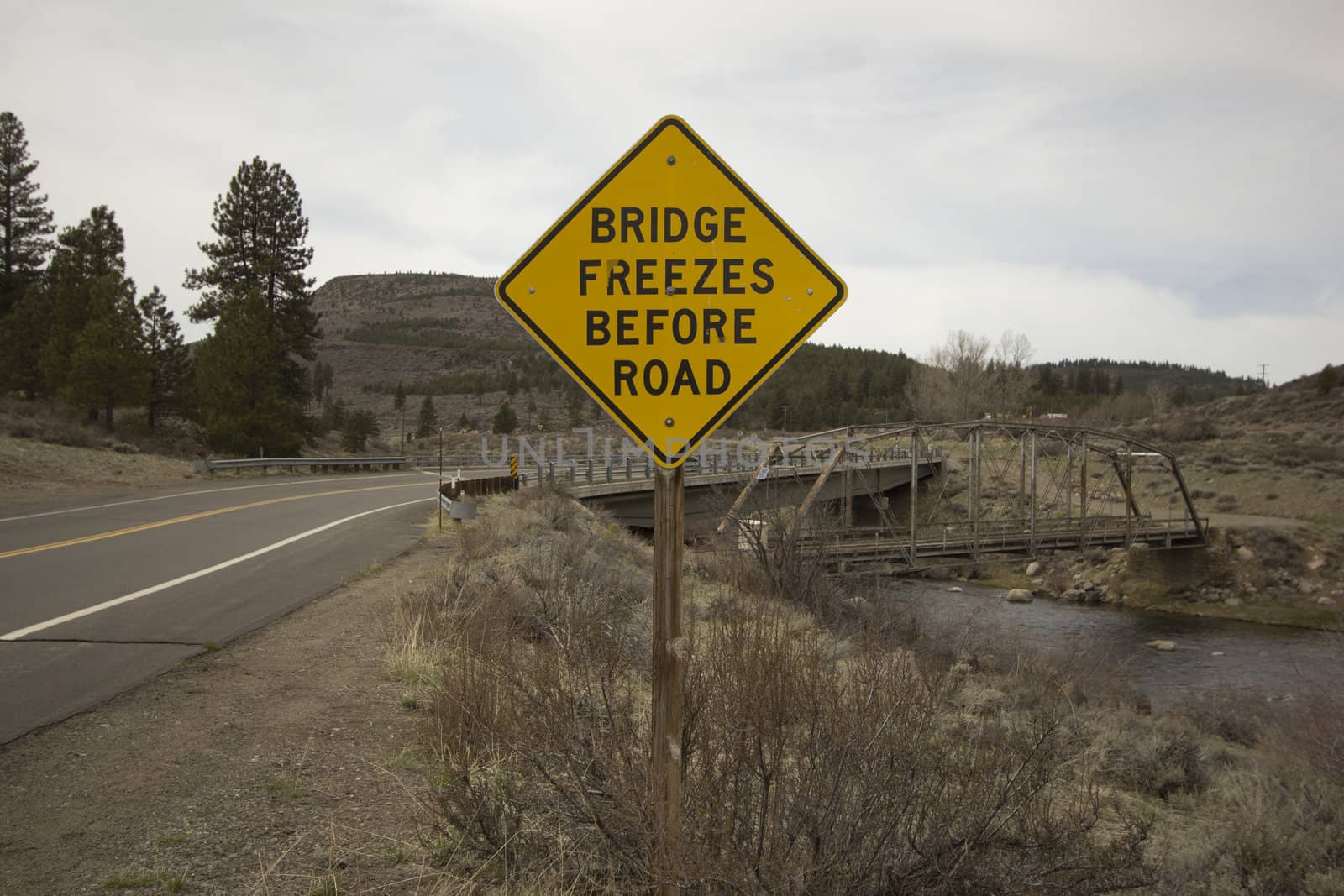 bridge freezes before road sign next to river