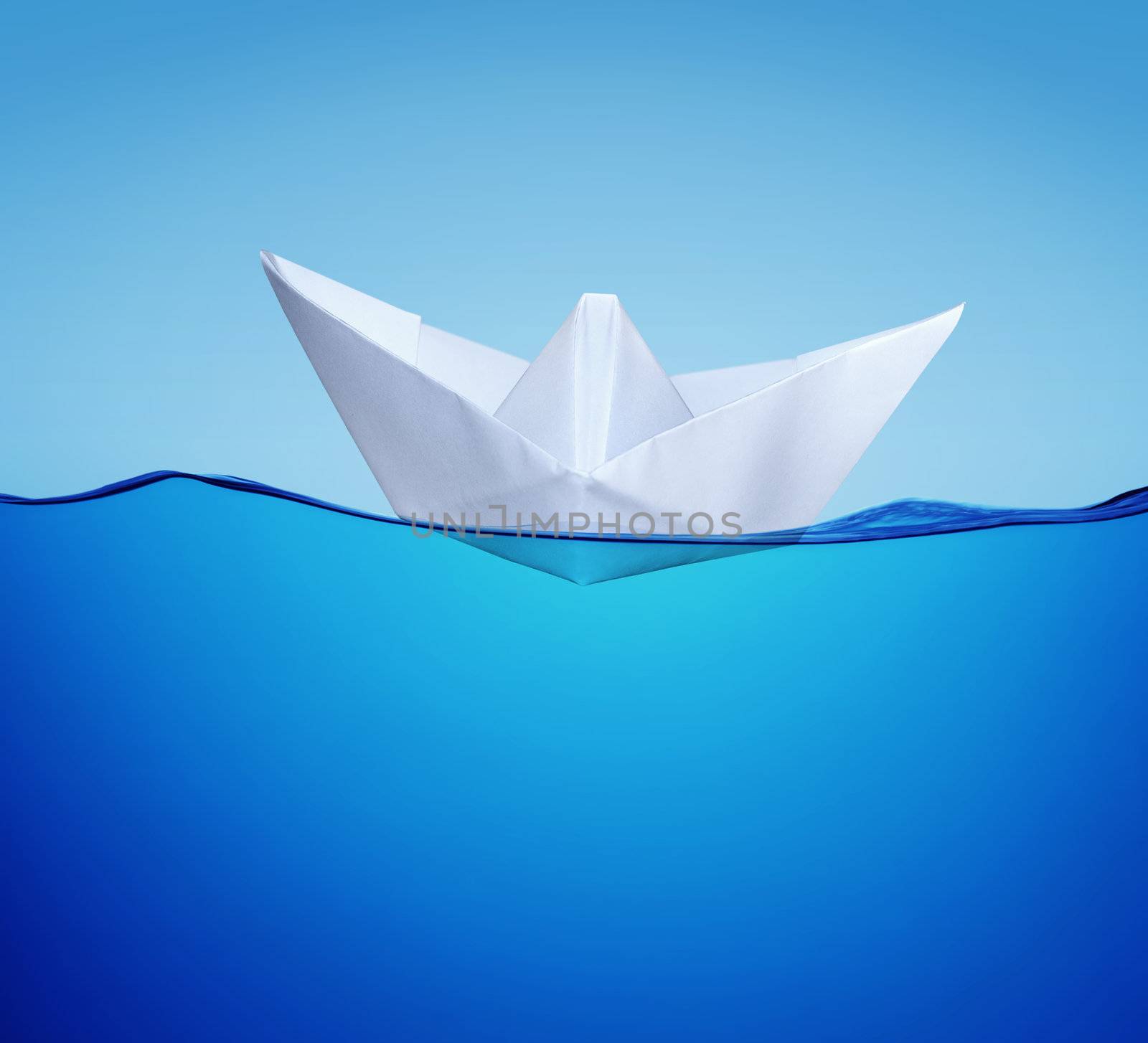 white paper toy-ship on the blue water in half face view