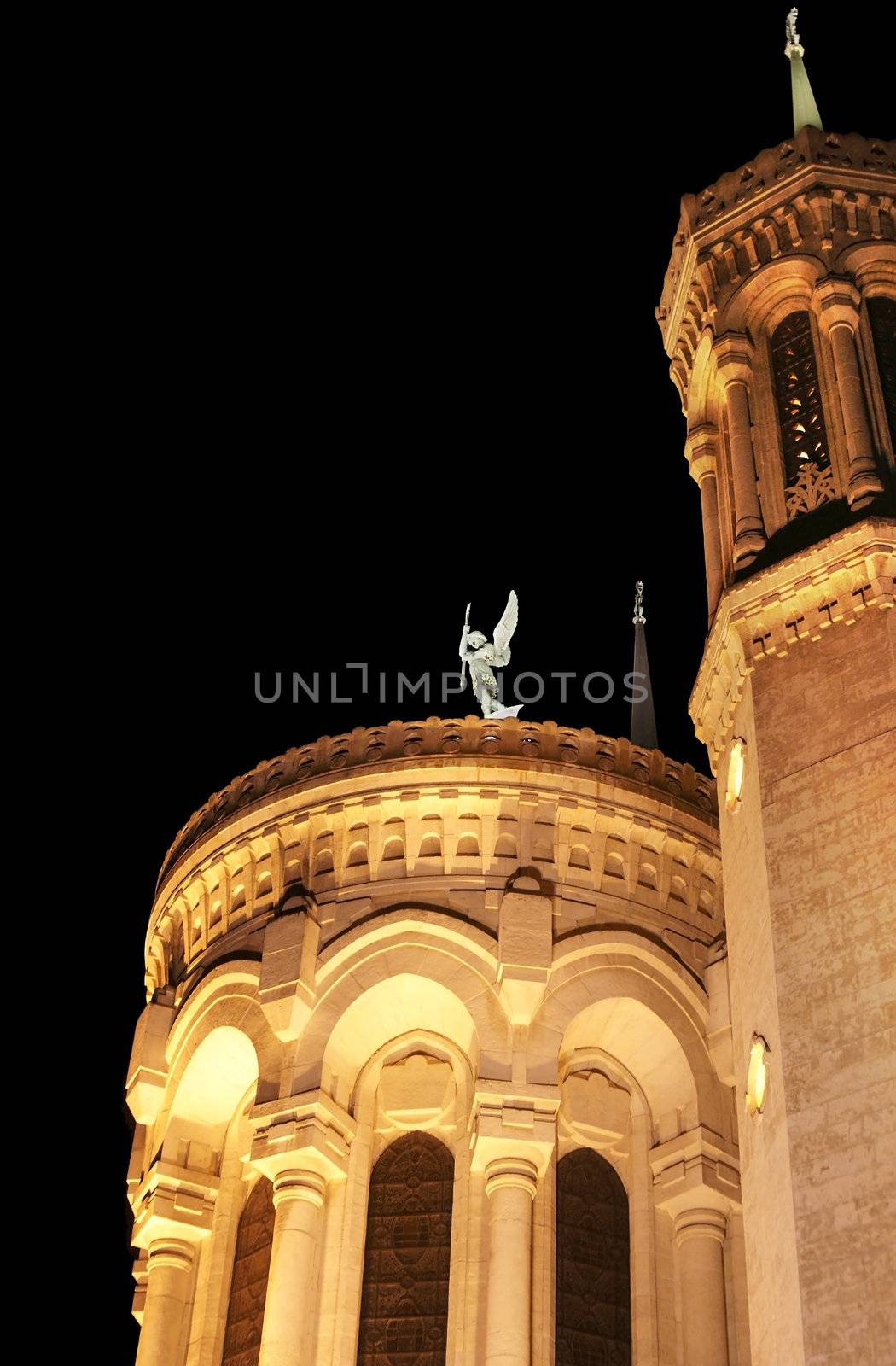 Notre-Dame de Fourviere basilica church at night with its beautiful architecture, tower and angel statue.