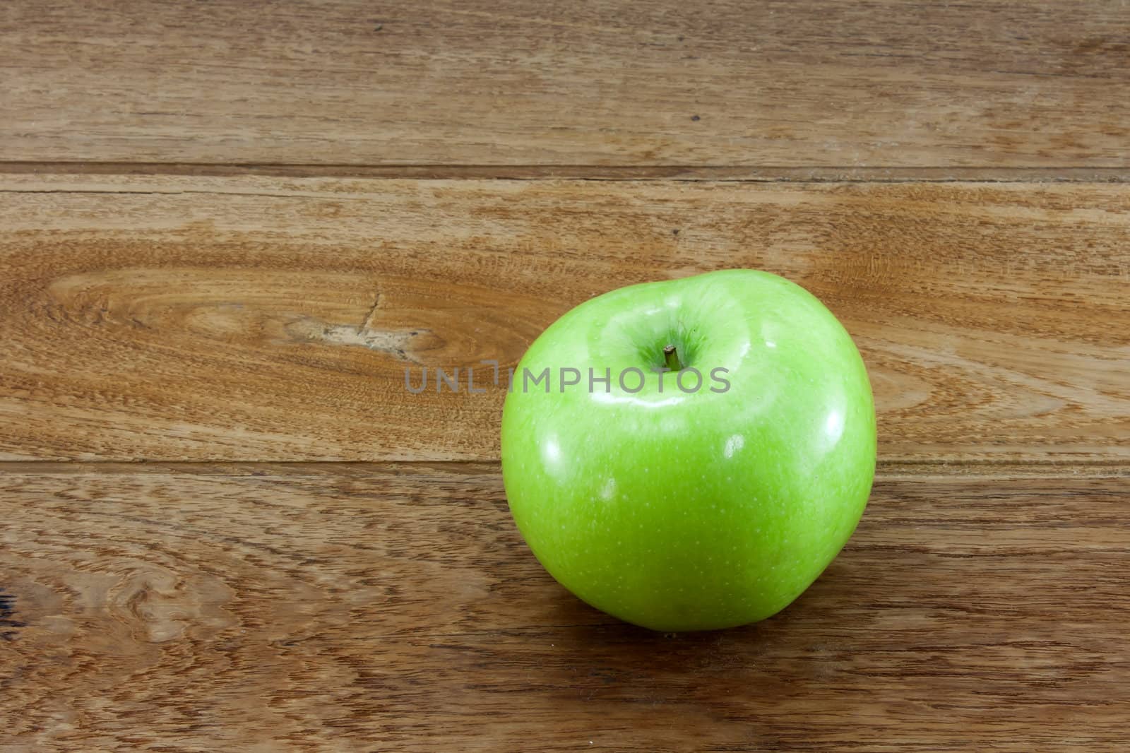 Single green apples on teakwood background.