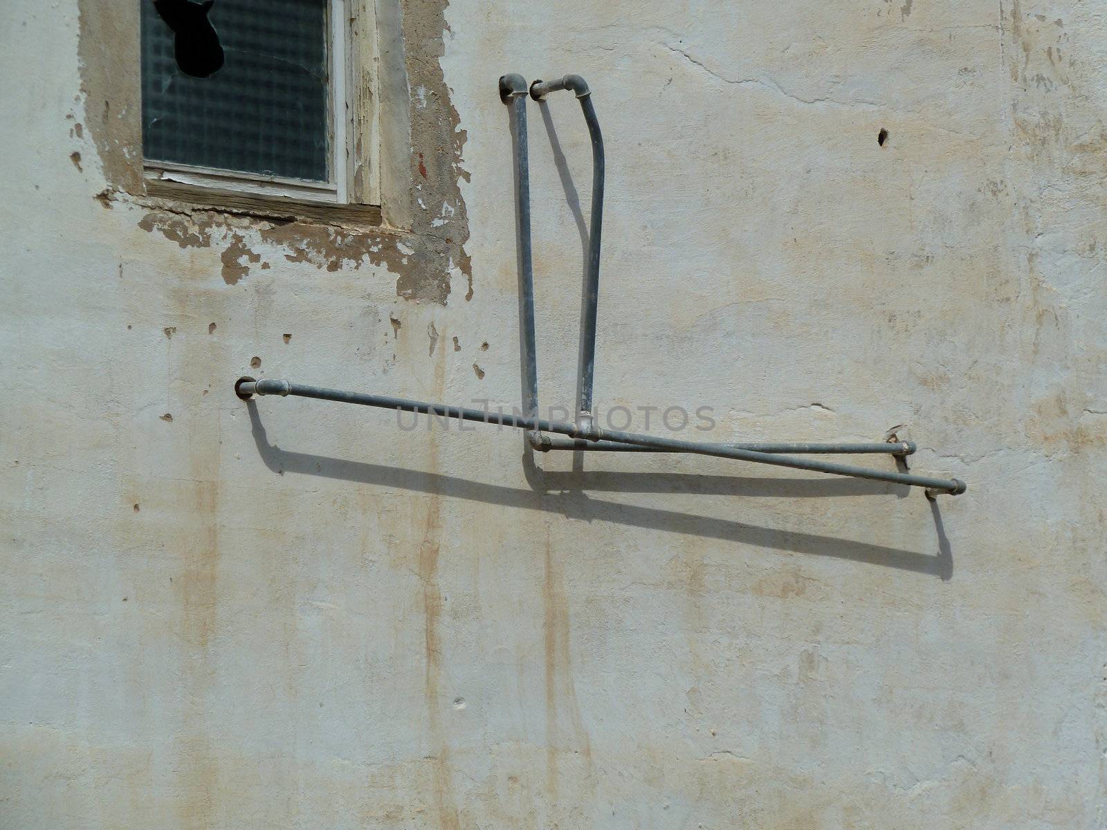 old external plumbing against a dirty white wall