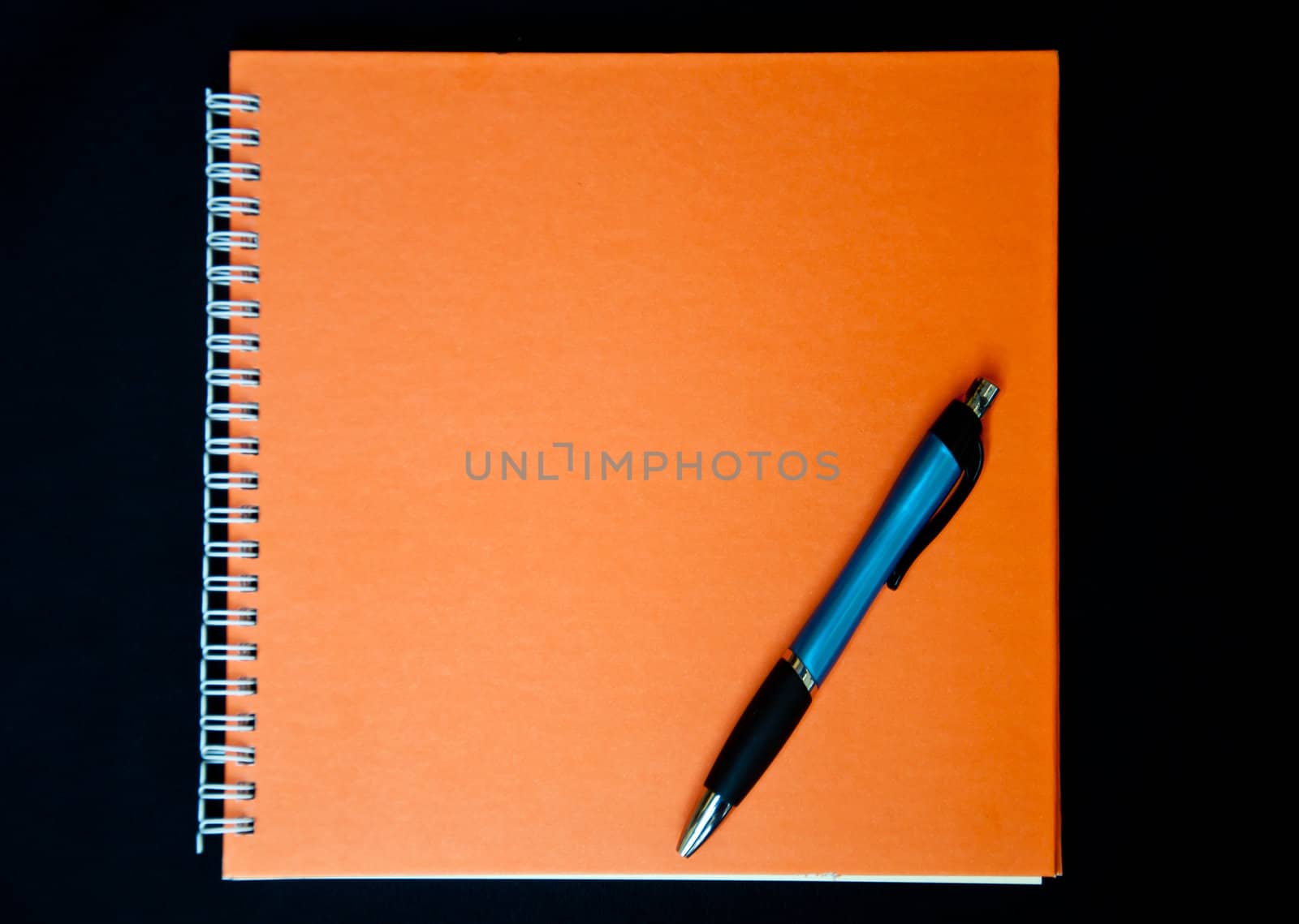 orange notebook and pen on black background