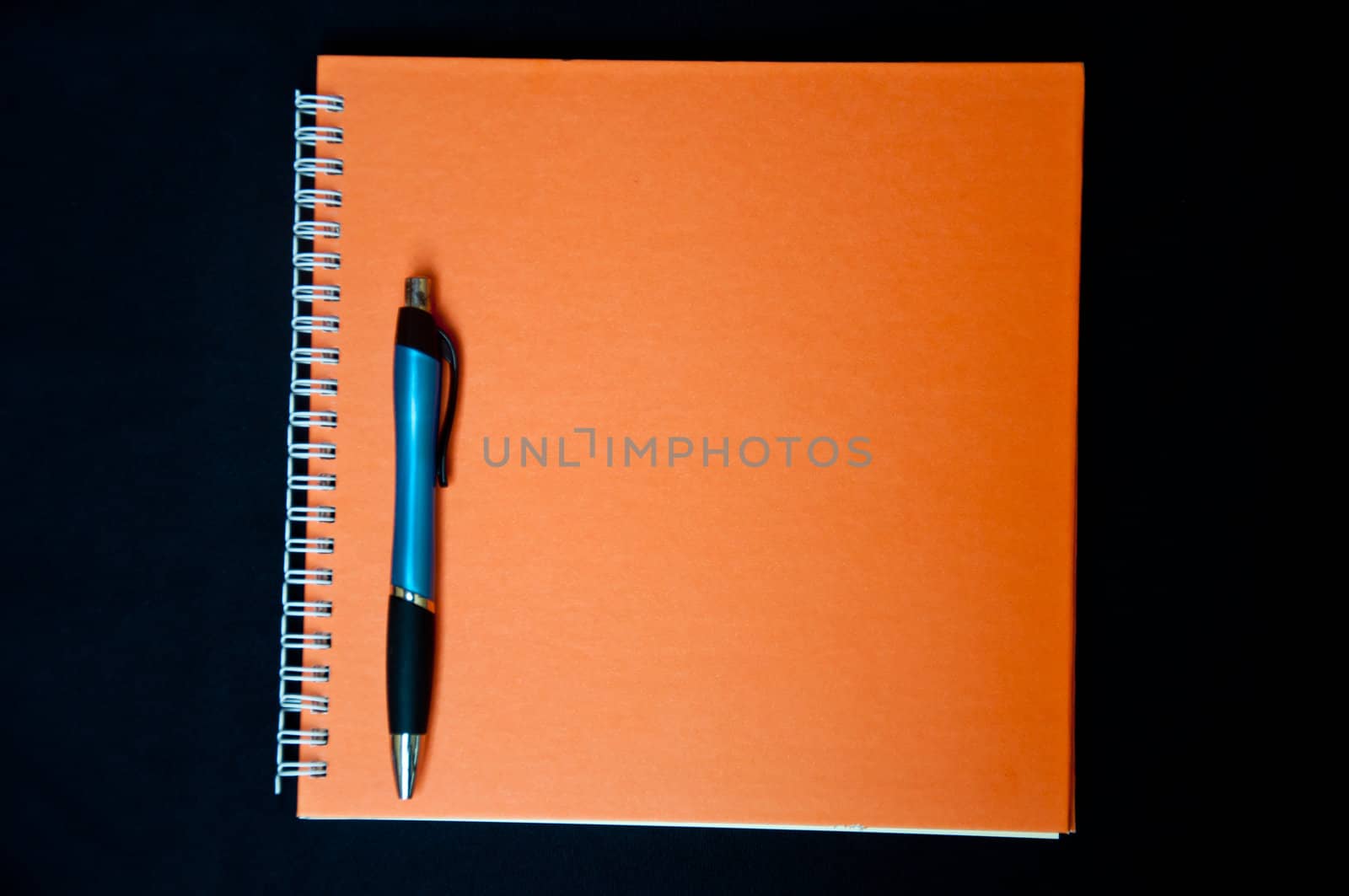 orange notebook and pen on black background