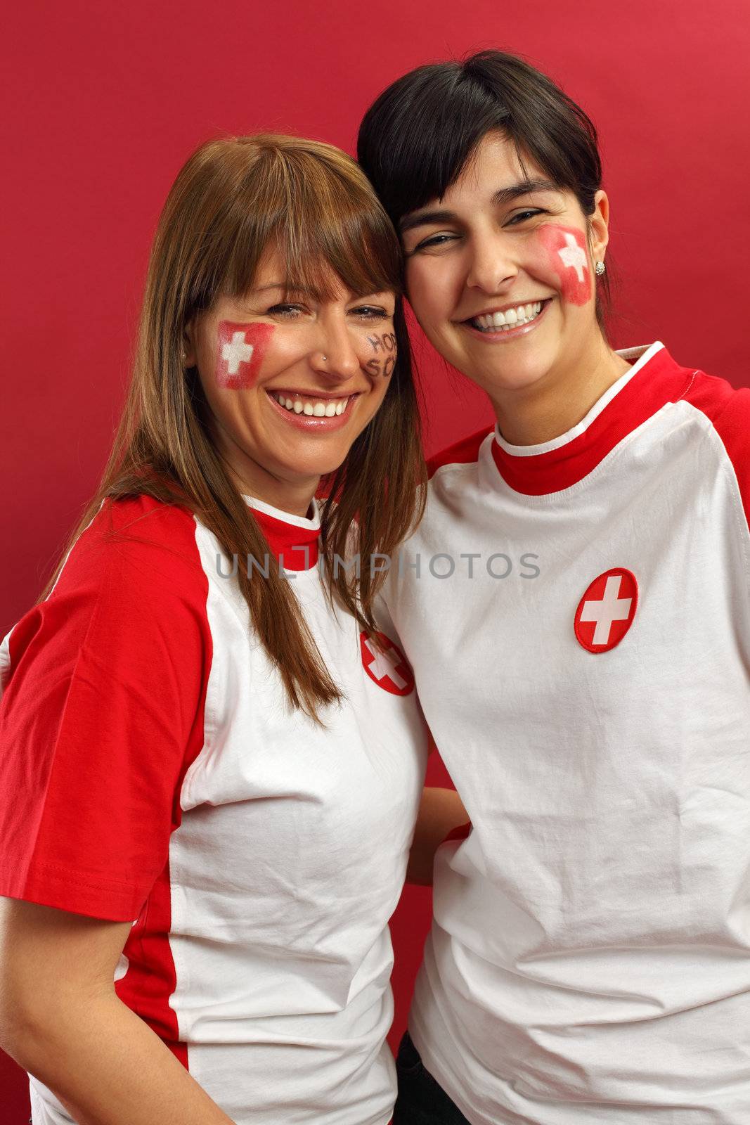 Photo of two female Swiss sports fans smiling and cheering for their team.