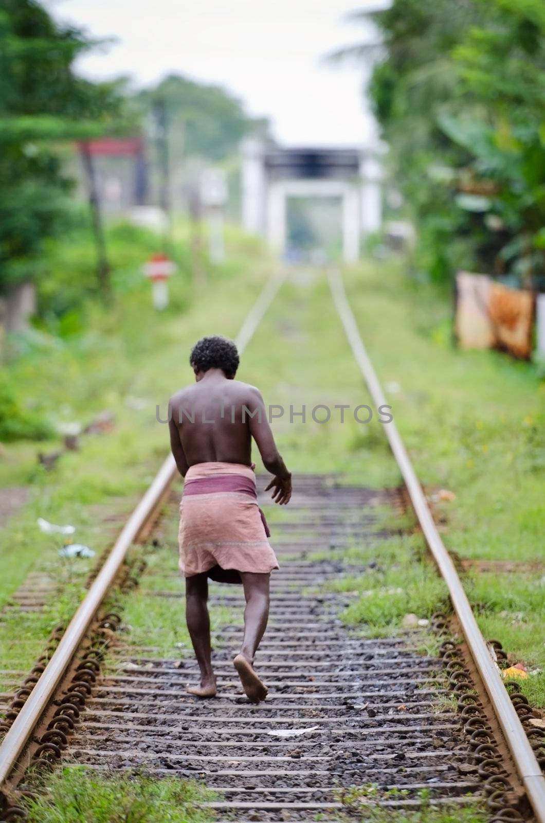 Bendota, Sri Lanka - December 14, 2011: Lonely unidentified asian man in traditional dress sarong on railway lines.