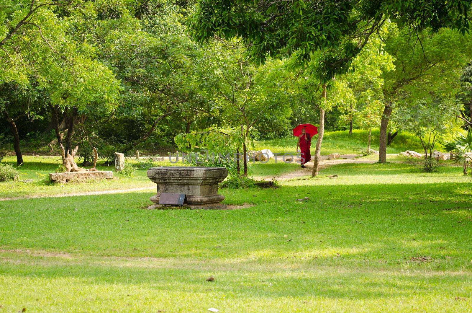 Anuradhapura, Sri Lanka - December 5, 2011:  Buddhism monk with red clothes and umbrella follow path in ruined old temple