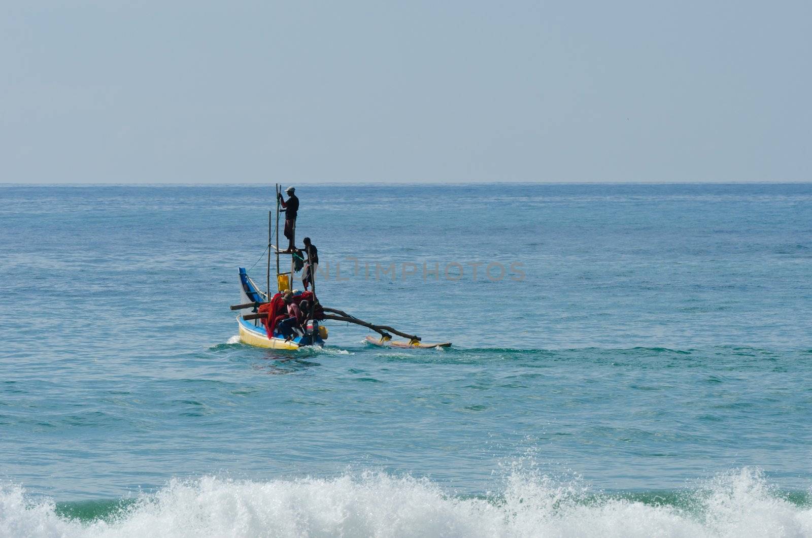 Mirissa, Sri Lanka - December 12, 2011: Traditional Asian small motorboat with four fishermen and fishing net.