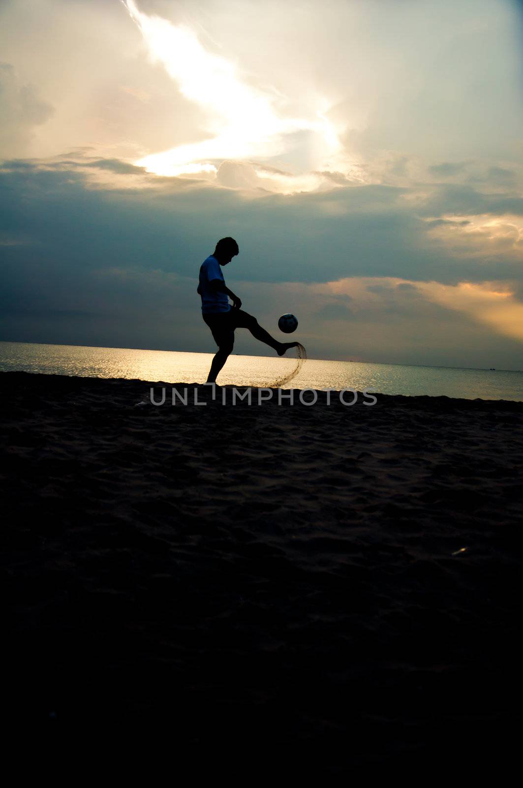 silhouette of man playing soccer on the beach