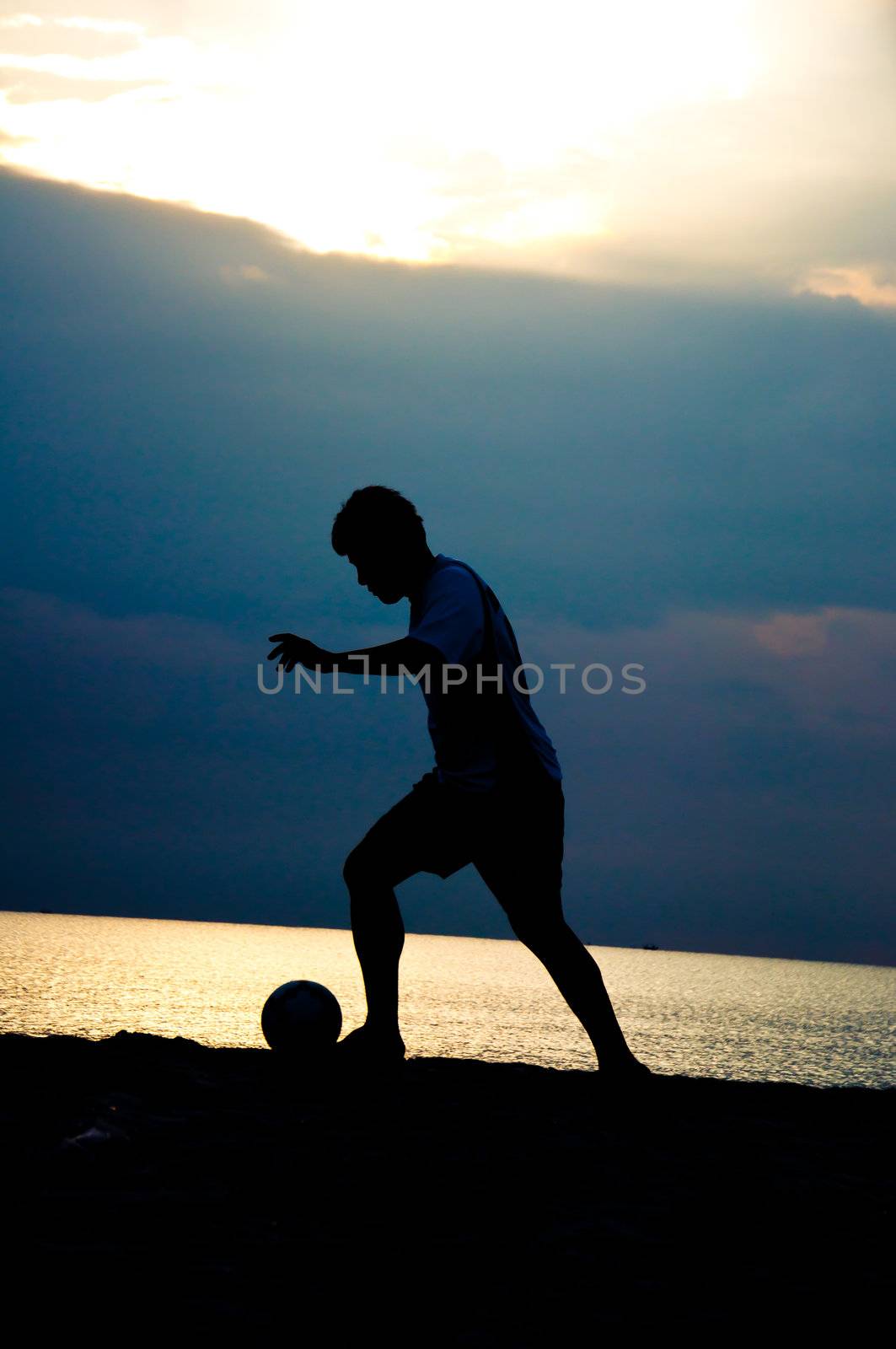 silhouette of man playing soccer on the beach