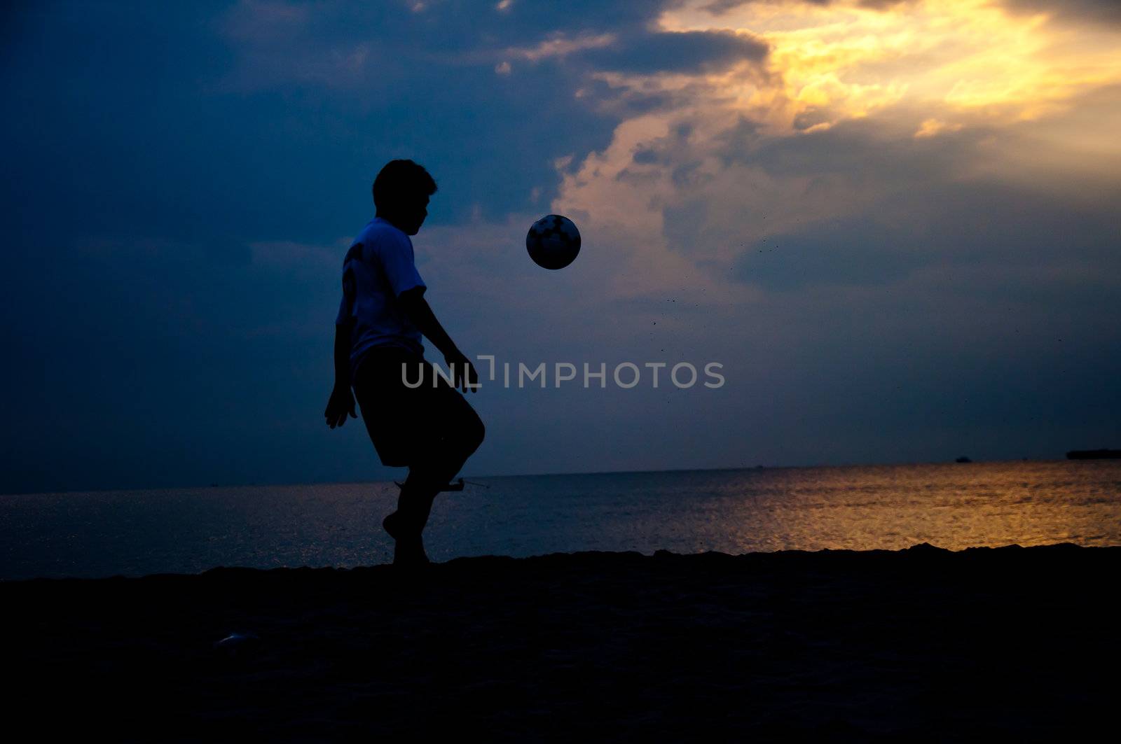 silhouette of man playing soccer on the beach