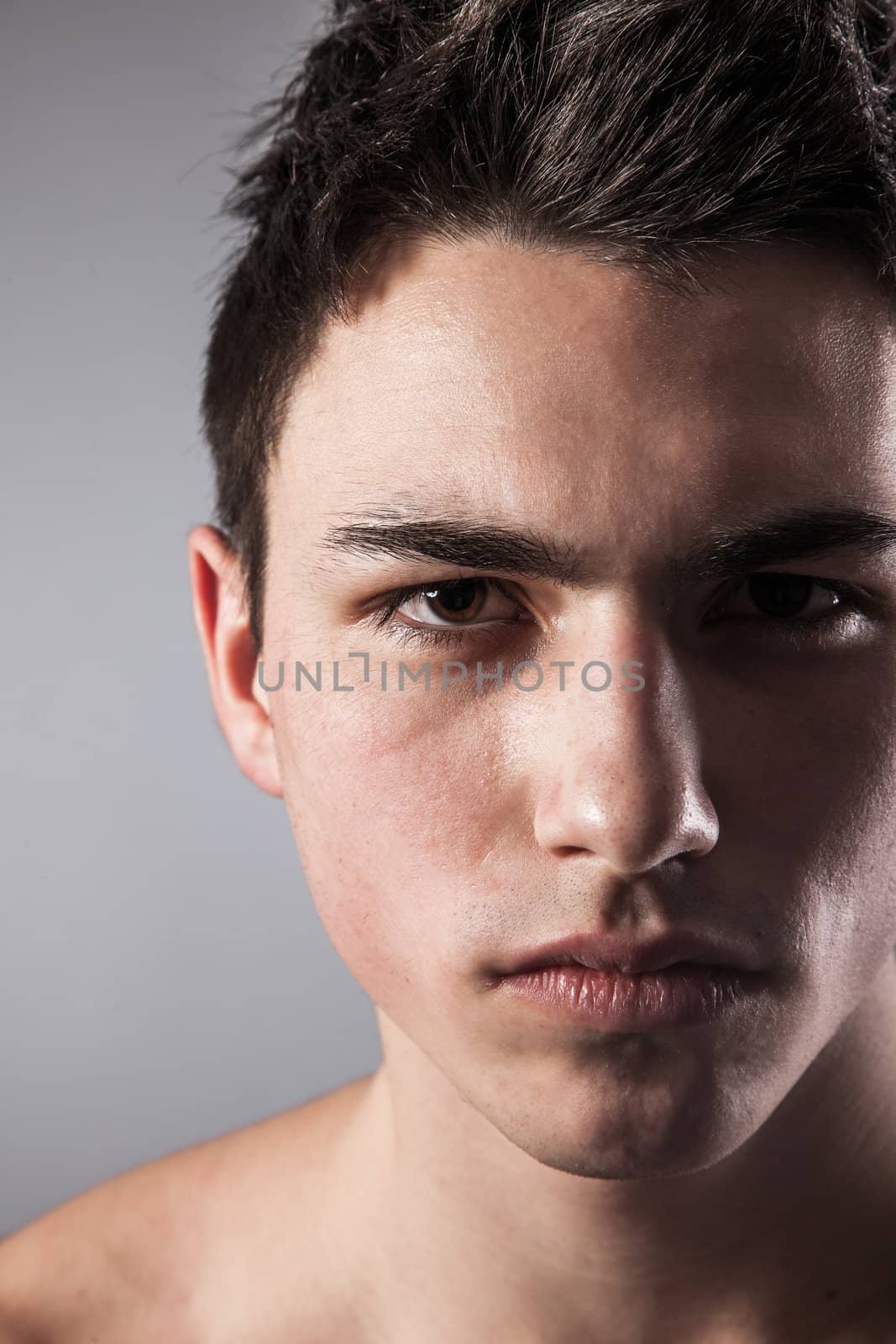 Handsome face of a young man. Isolated on grey background.