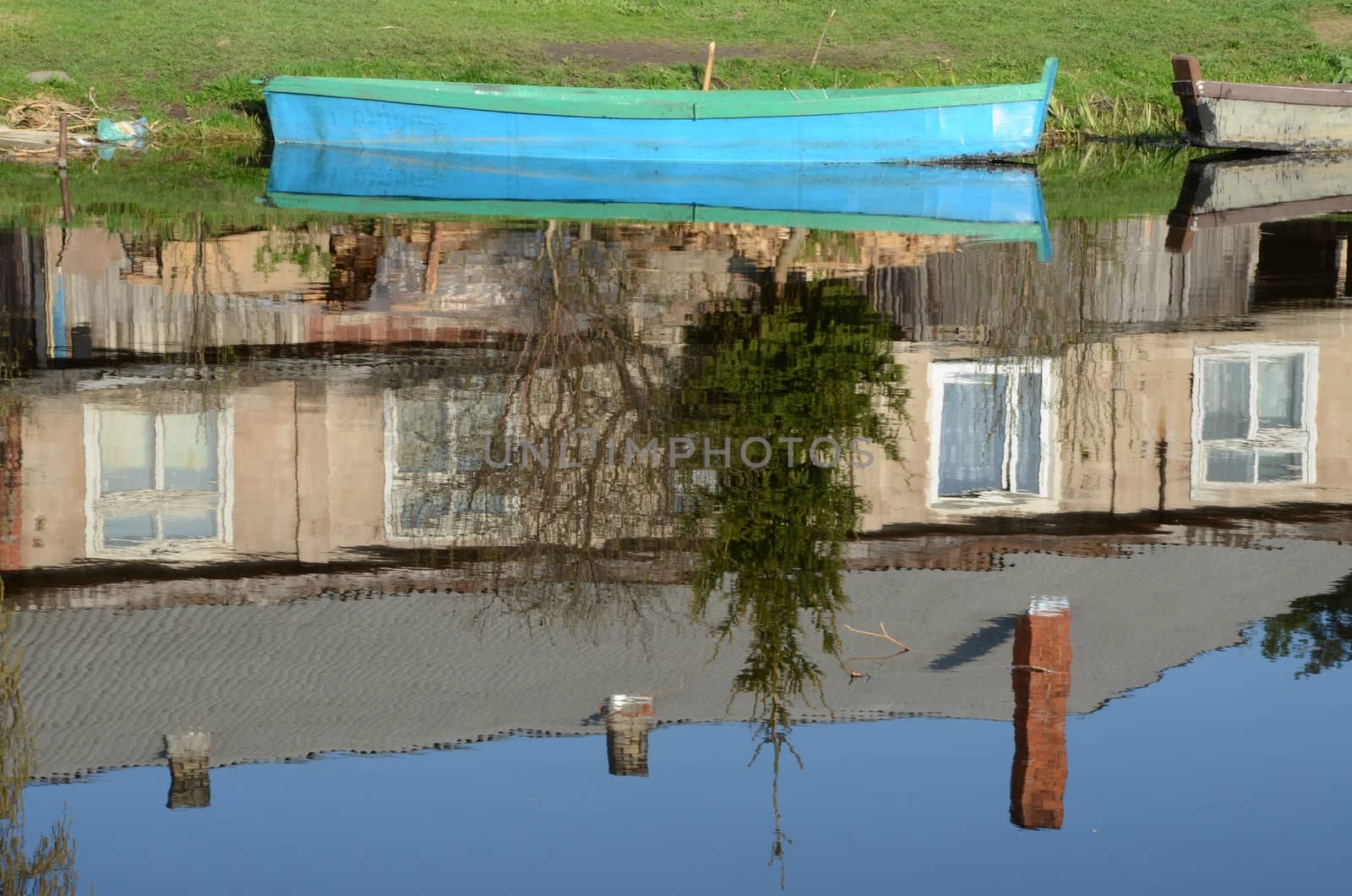 boats standing on river coast and mirrow reflections of old house on water.