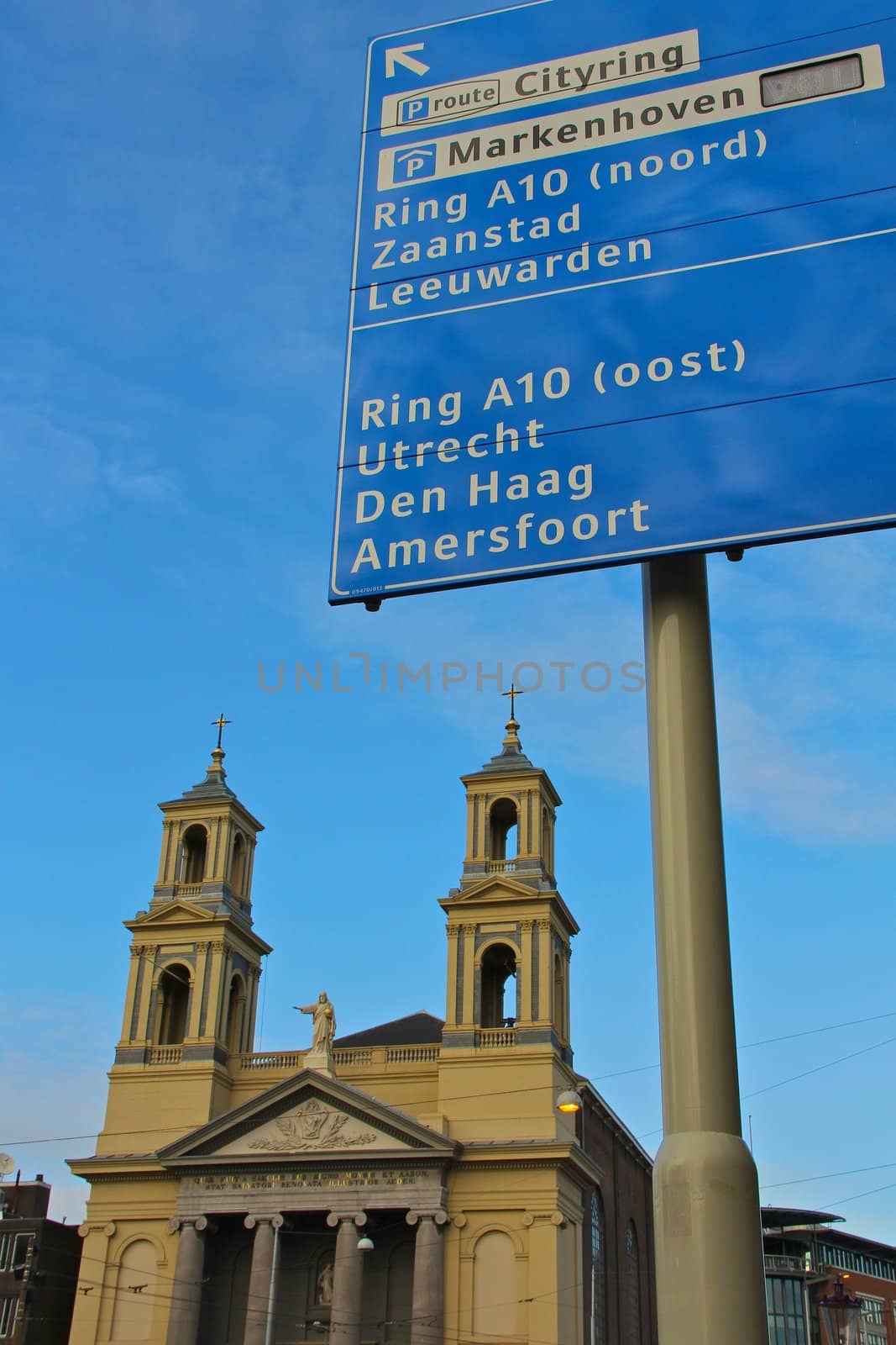 Foreground Roadsign, Background Christian Church, at Waterlooplein, Amsterdam, The Netherlands with a bright Blue Sky. Portrait Orientation.