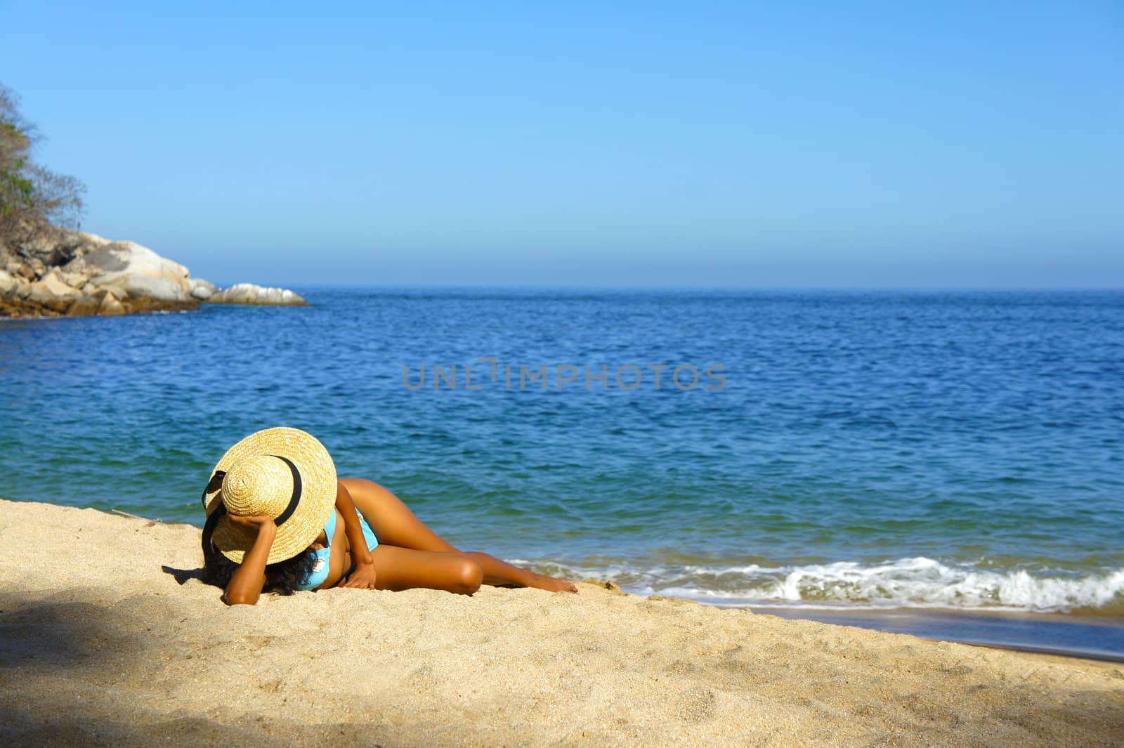 Young woman lying on beach sun tanning.