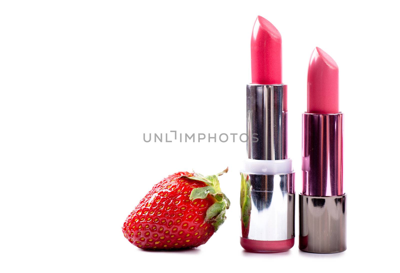 Two lipsticks and a strawberry isolated over white background