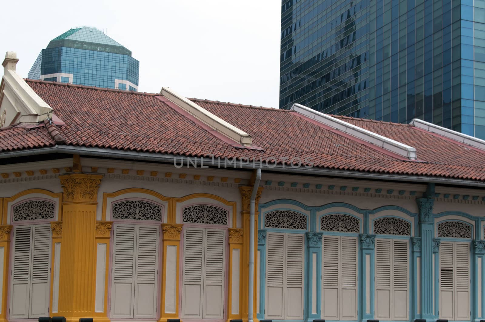 singapore - colonial architecture of colorful old houses in front of modern skyscrapers