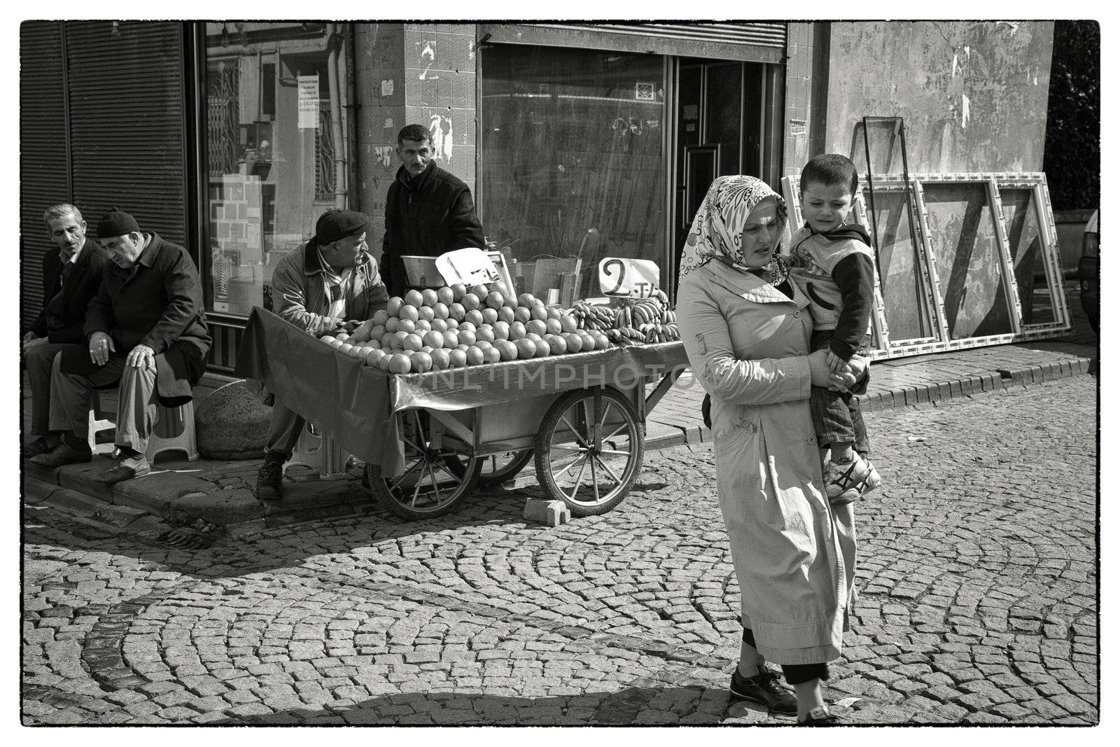 TURKISH MOTHER AND CHILD, ISTANBUL, TURKEY, APRIL 11, 2012: Mother and child passing vendor greengrocer in the Fatih district of Istanbul, Turkey.