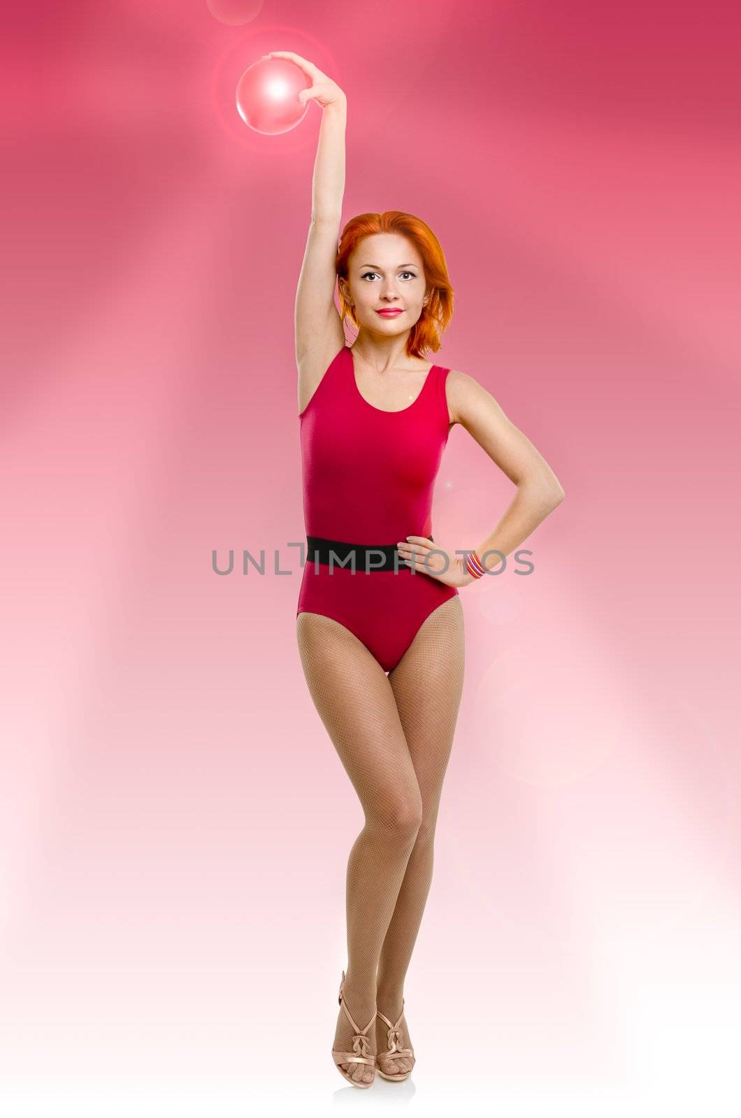 Slim fitness model standing with radiant fitball on pink background