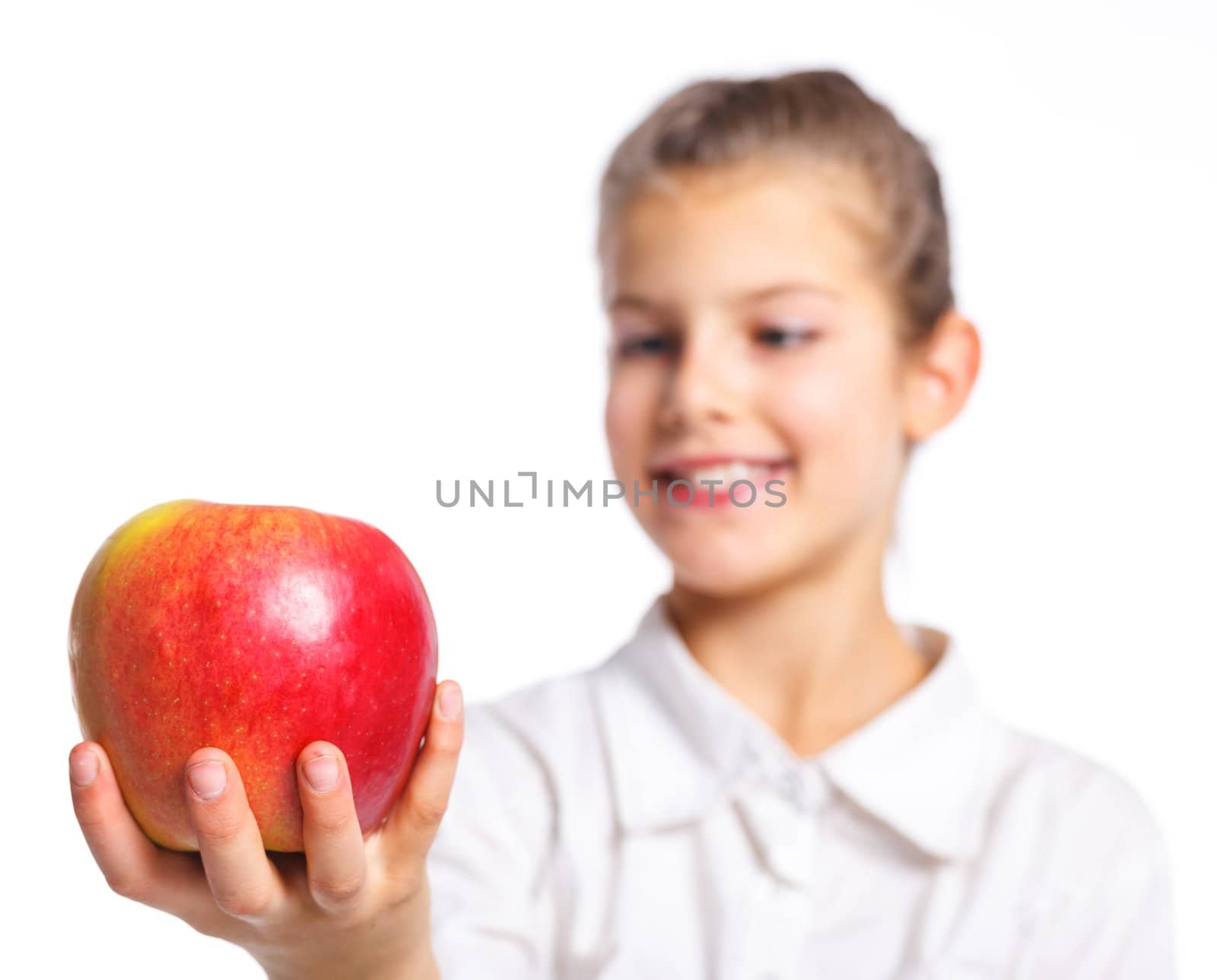 Portrait of happy cute little girl with apple. Focus on the apple. Isolated over white background.