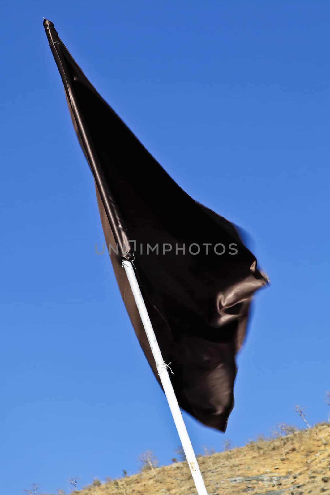 Diagonal shot, portrait, vertical of a plain silky black flag waving in a gentle breeze