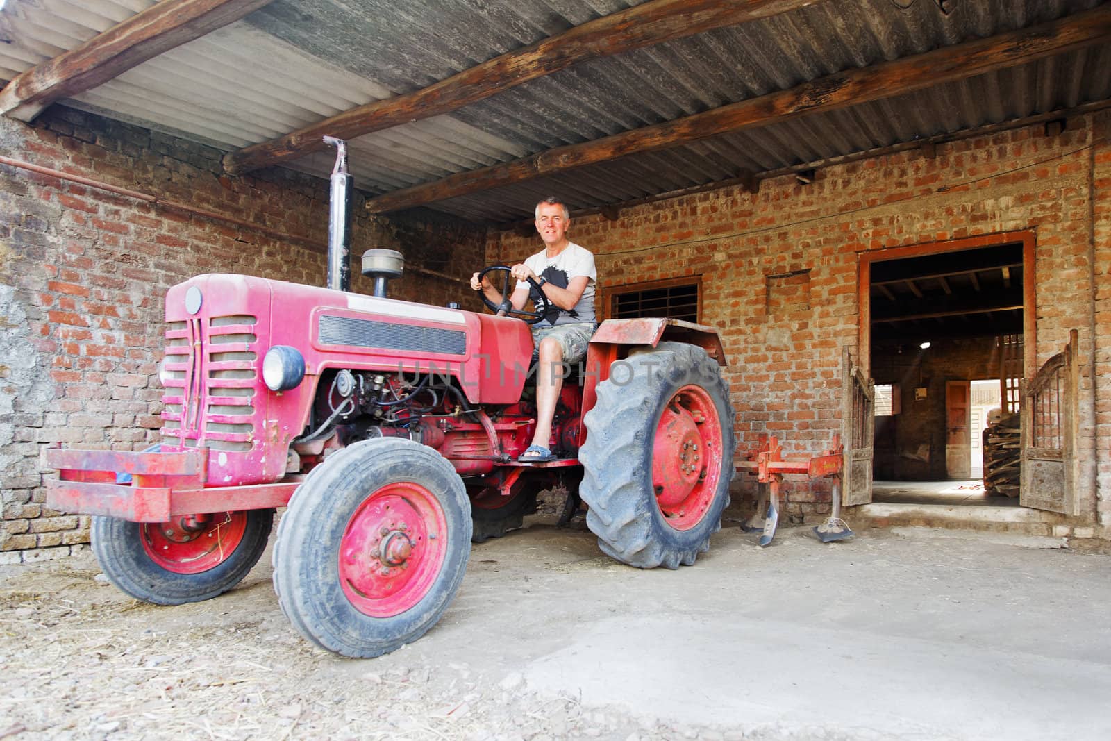 Happy farm hand on a tractor about to move off on his daily rounds