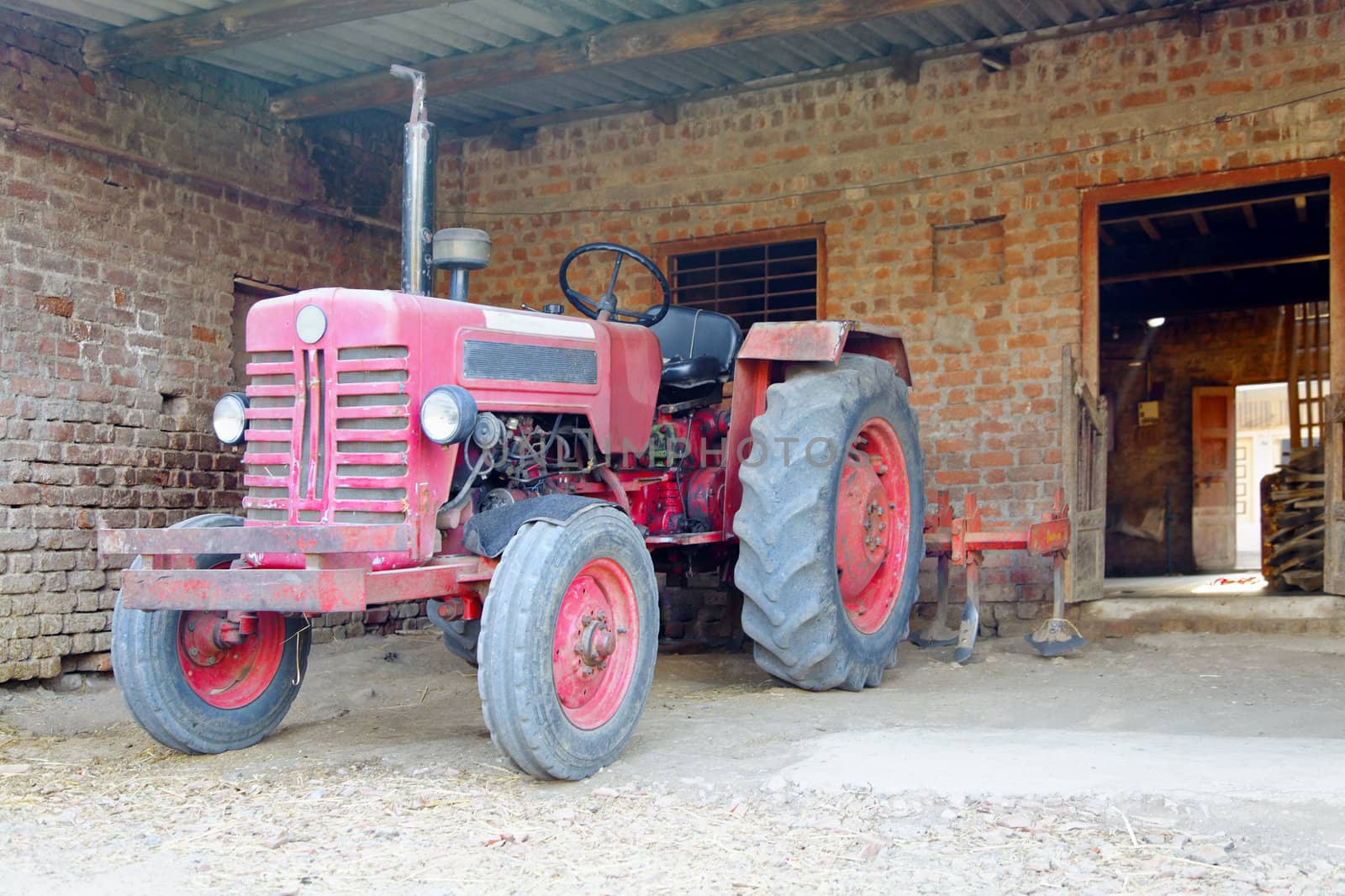 Landscape of Indian tractor parked in a stable with ploughing attachment