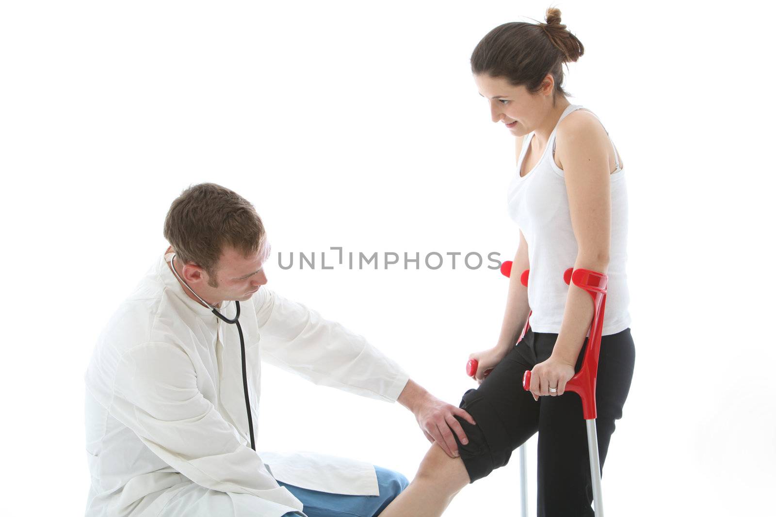 Orthopaedic surgeon examining the knee of a female patient on crutches during a post operative check-up