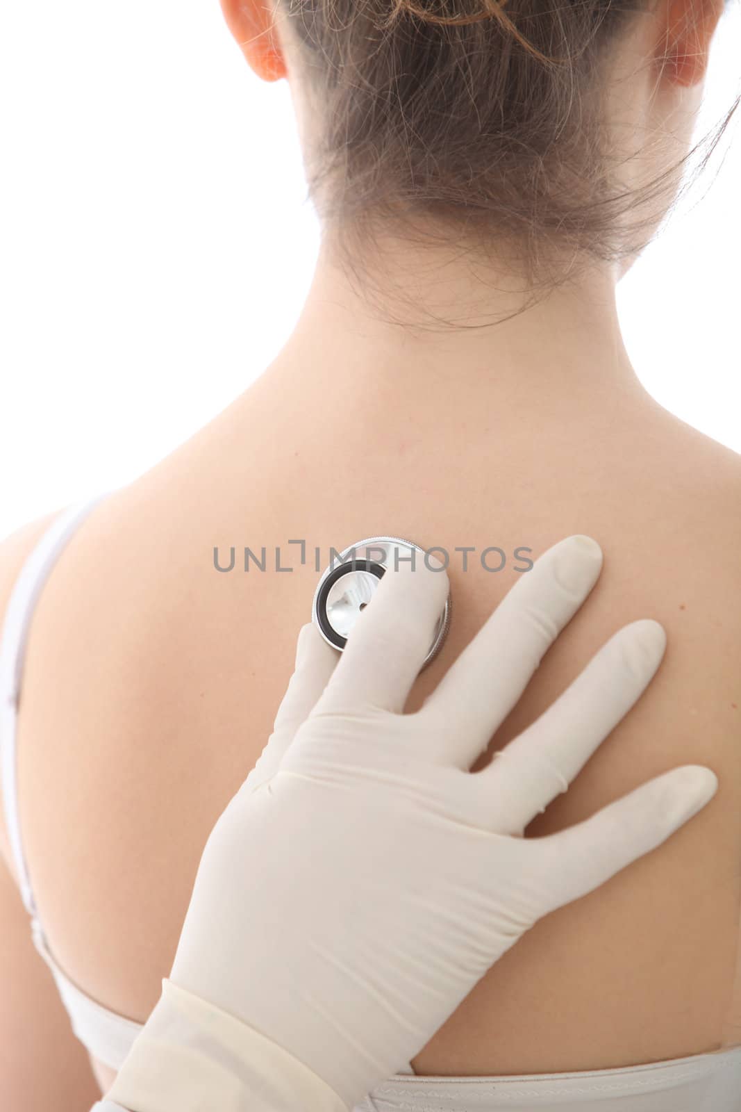 Gloved hand holding the disc on a stethoscope to a female back in order to listen to the lungs and heart