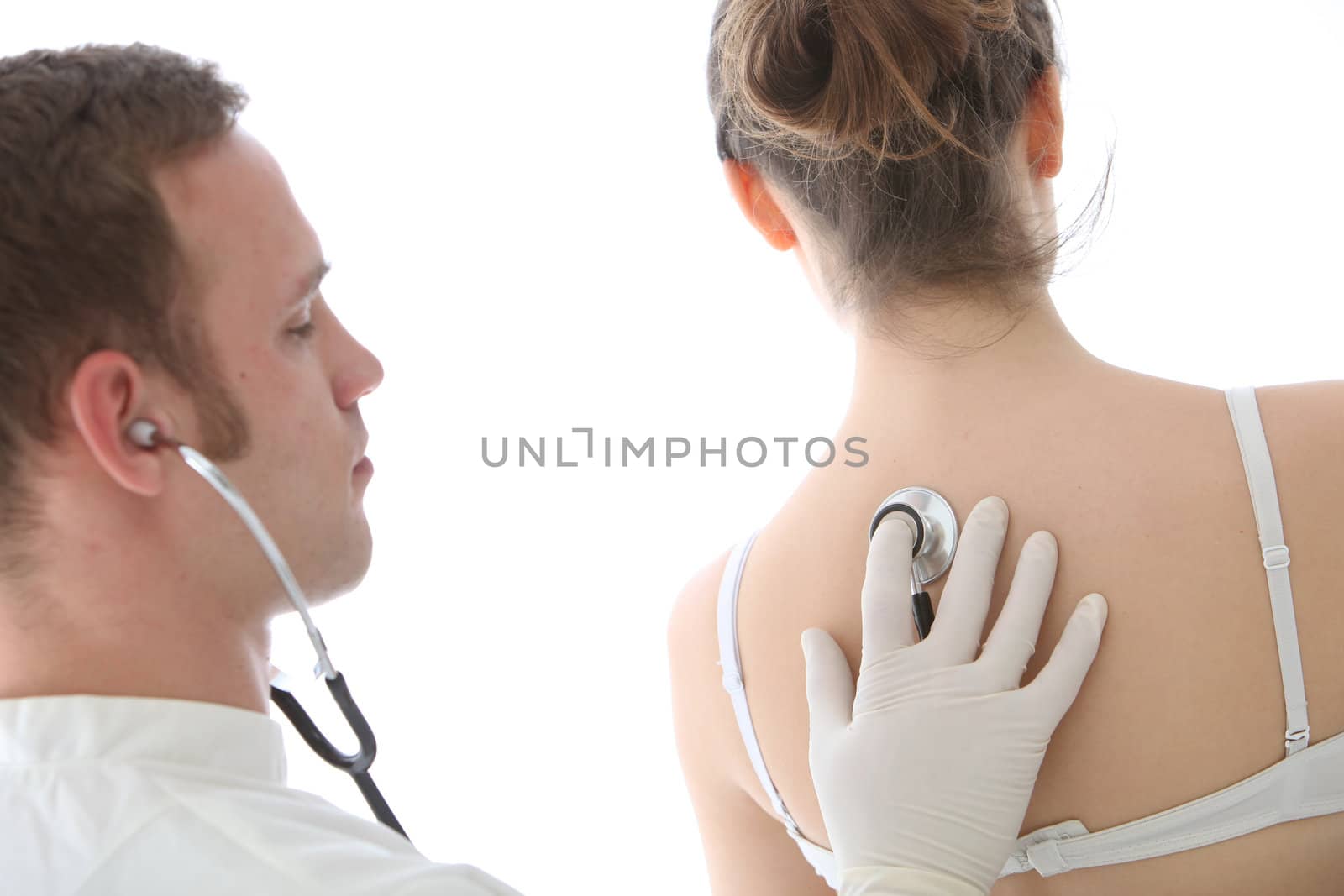 Young male doctor using a stethoscope to listen to his female patient breathing