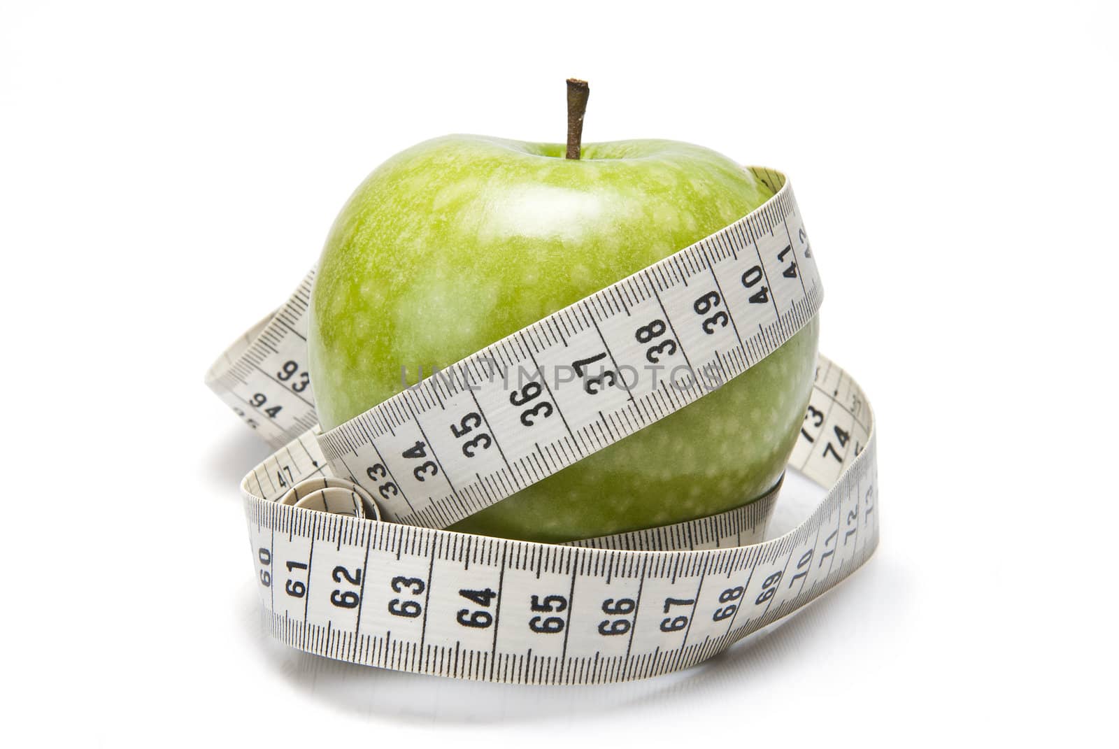 Measuring tape wrapped around a green apple as a symbol of diet.