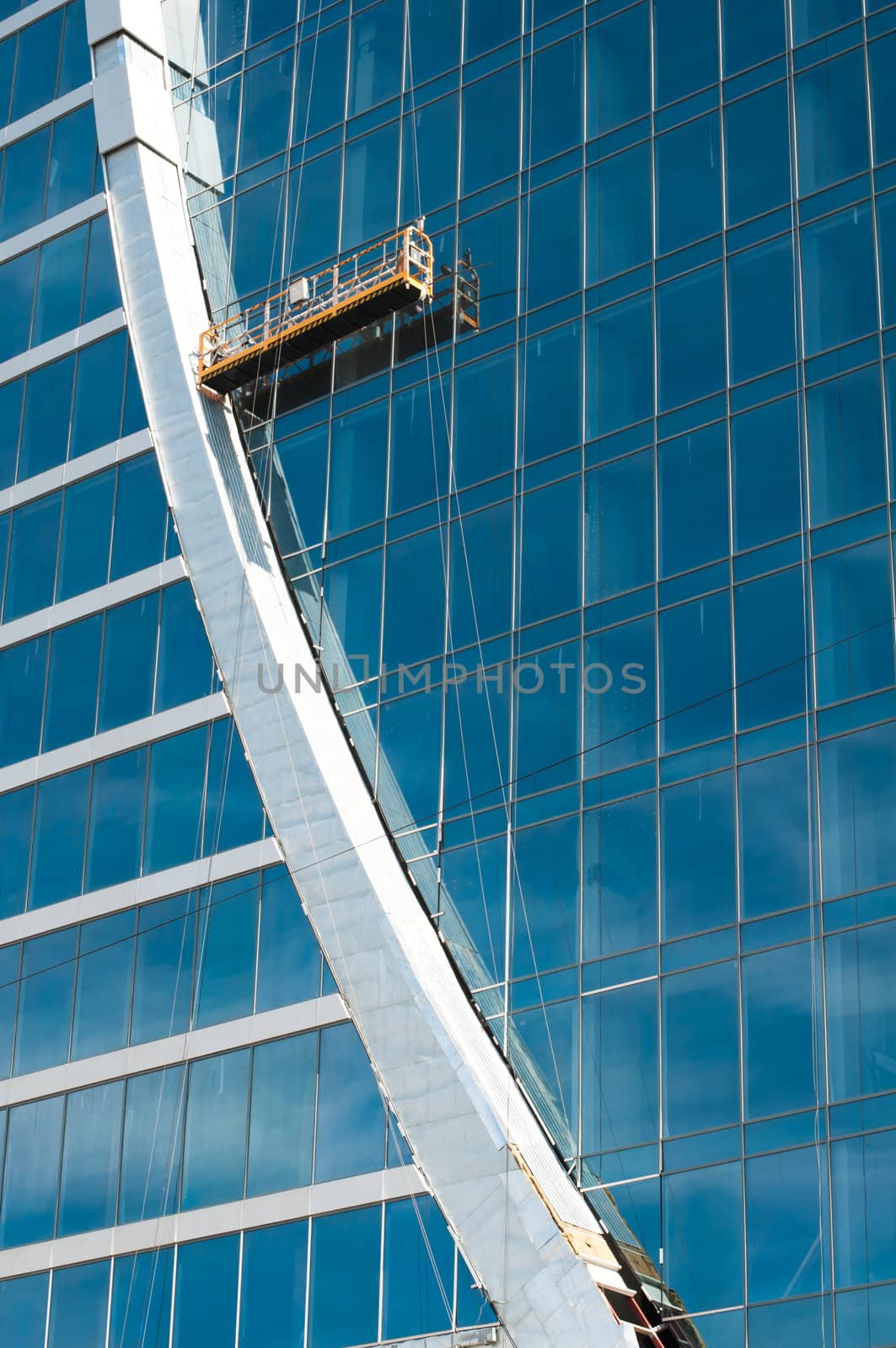 The glass wall of office building with windows and construction lift