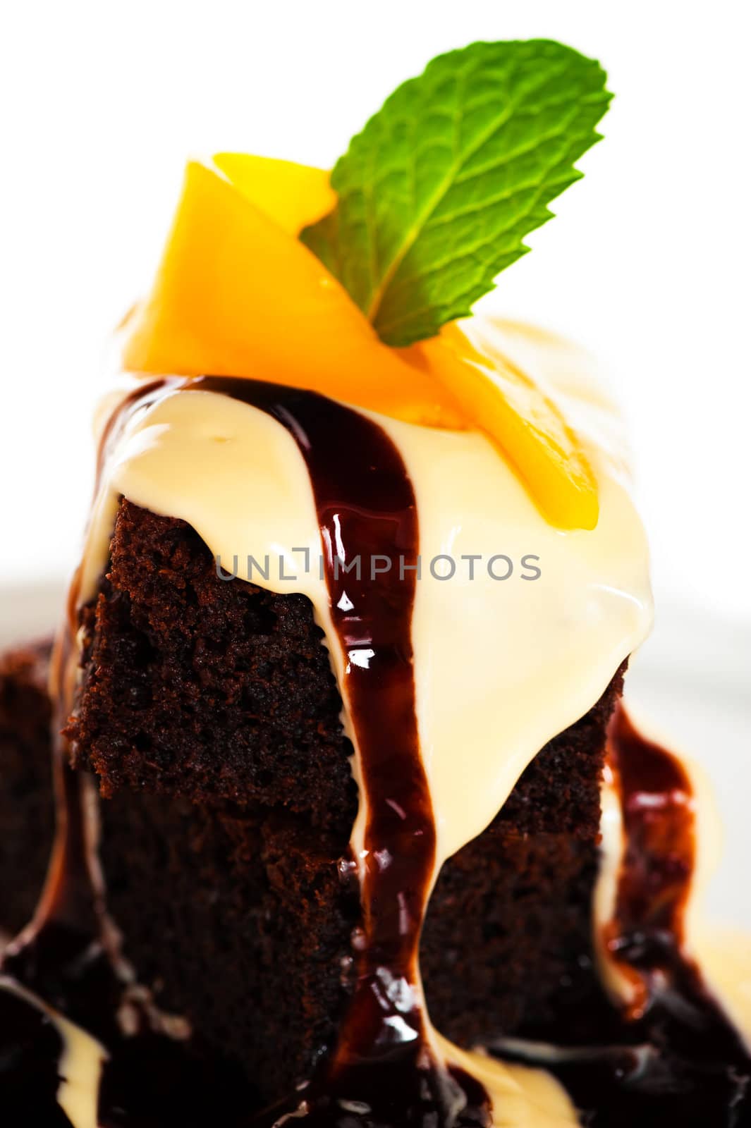 A plate with 2 pieces brownies white and brown chocolate and mango on white background as a studio shot