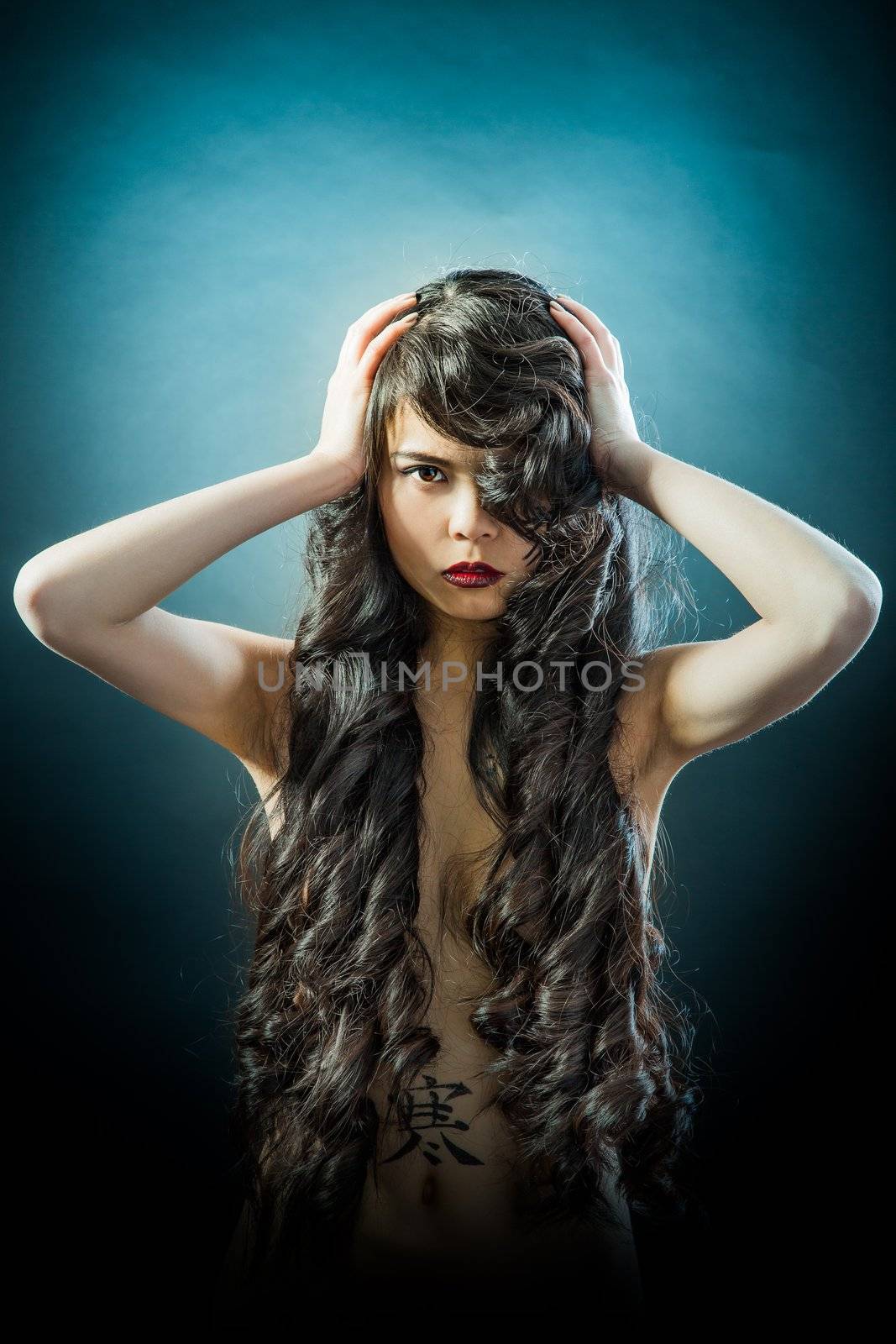 Beauty Portrait. Beautiful brunette Asian woman with long black hair. Shot in a studio on a black background