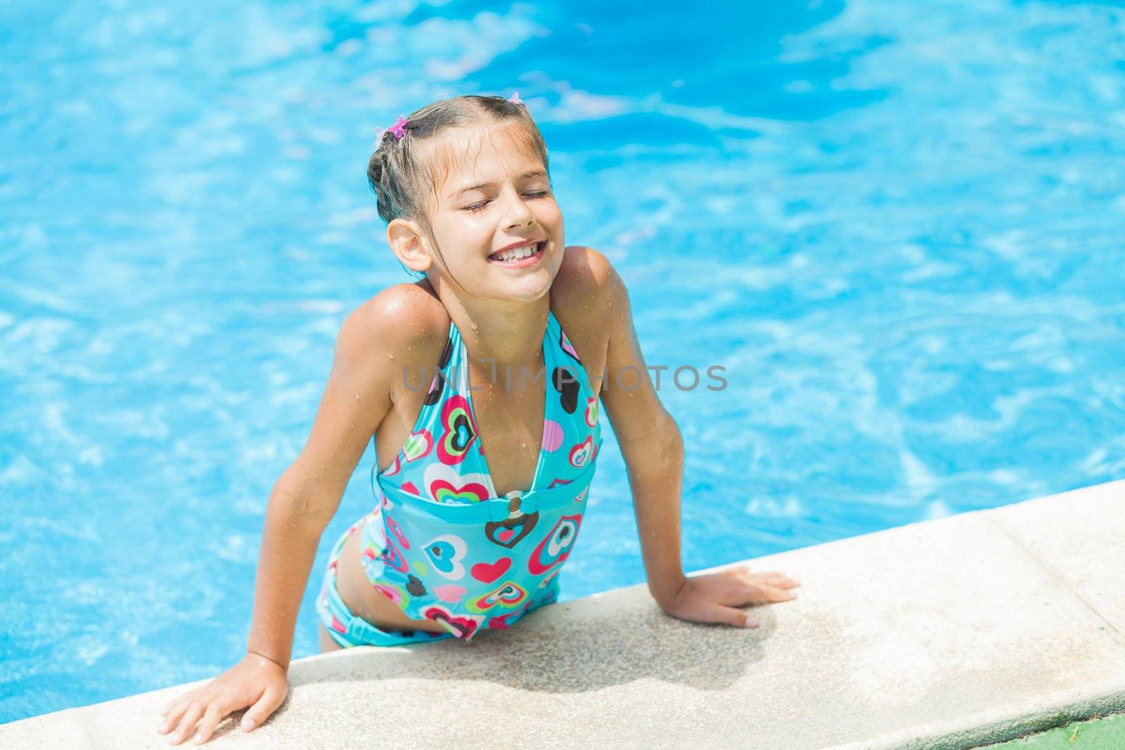 Pretty young smiling girl near a side of the pool