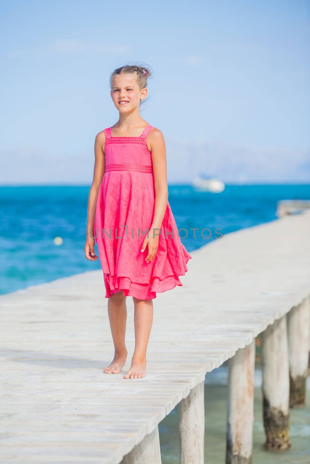 Cute teens girl walking on jetty with turquoise sea