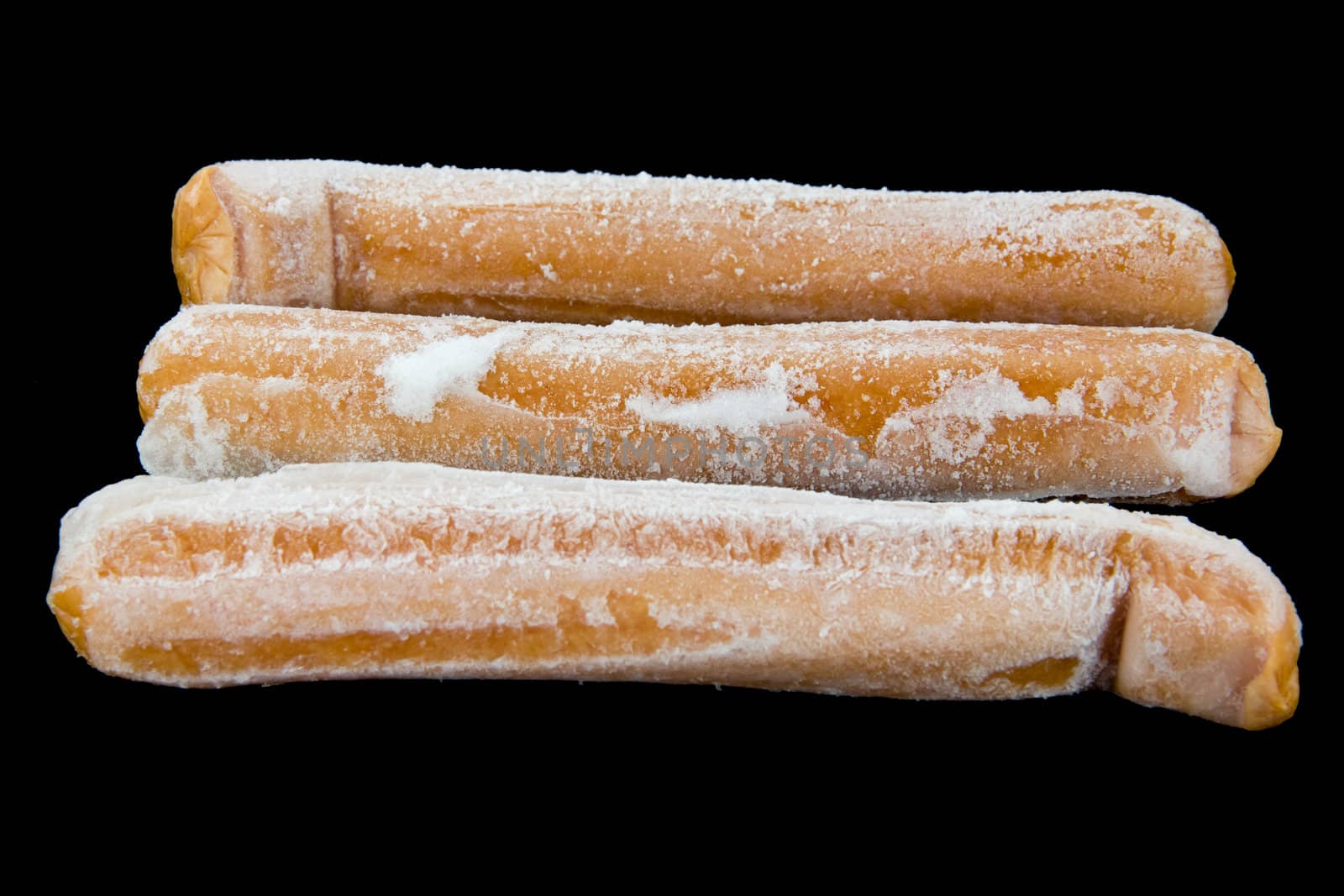 Picture of three frozen hot dogs on black