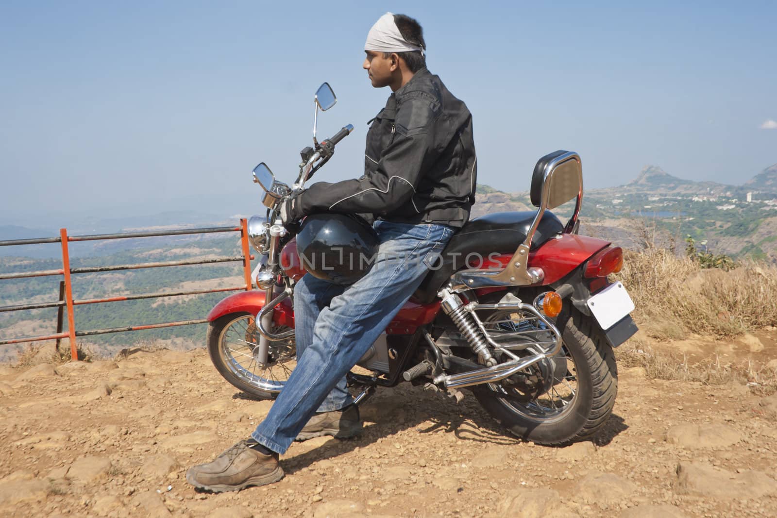 Biker on the cliff edge with a pondering expression looking over the valley at Tiger Point
