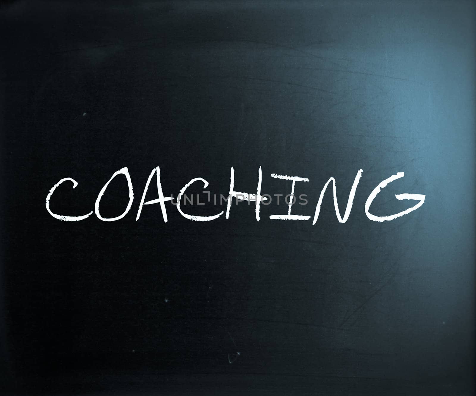 "Coaching" handwritten with white chalk on a blackboard.