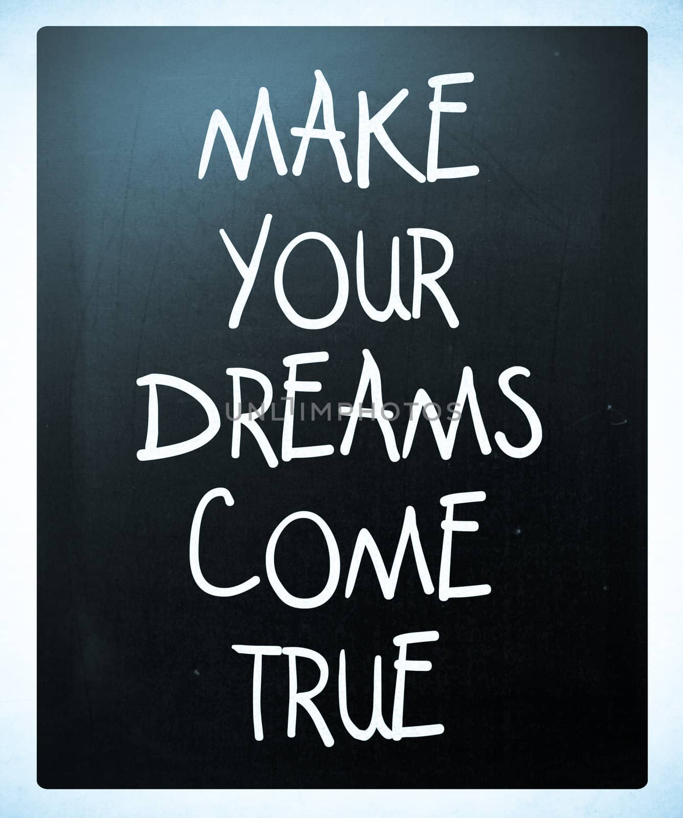 "Make your dreams come true" handwritten with white chalk on a blackboard