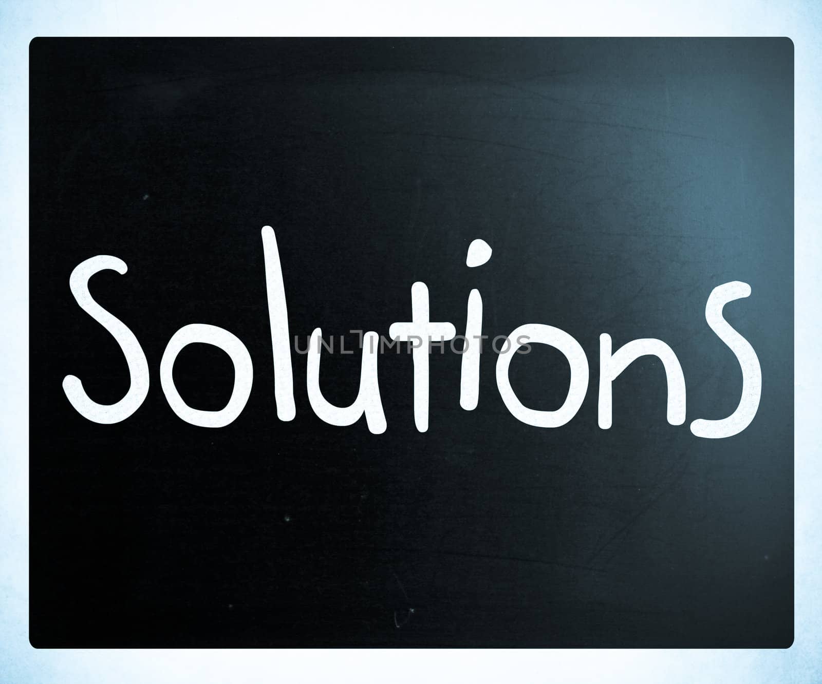 "Solutions" handwritten with white chalk on a blackboard