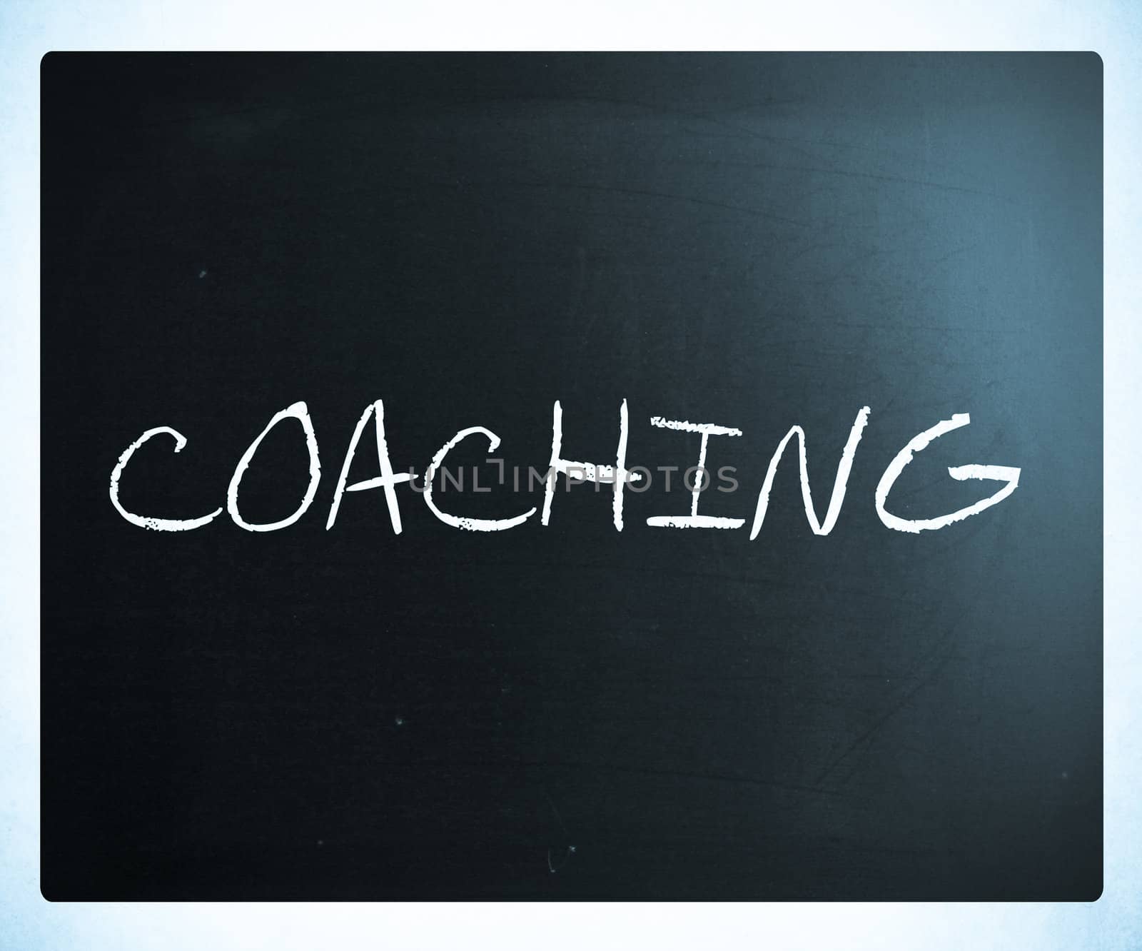 "Coaching" handwritten with white chalk on a blackboard.