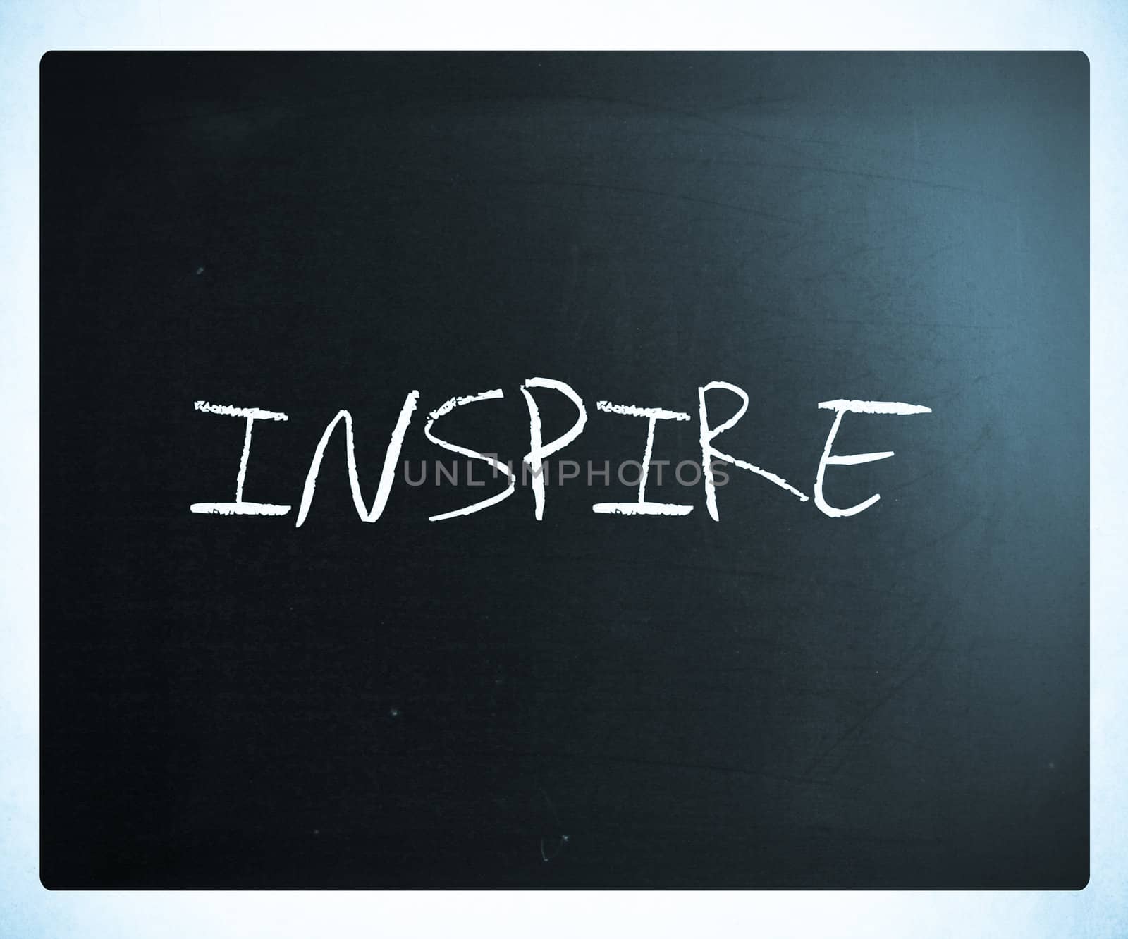 "Inspire" handwritten with white chalk on a blackboard.