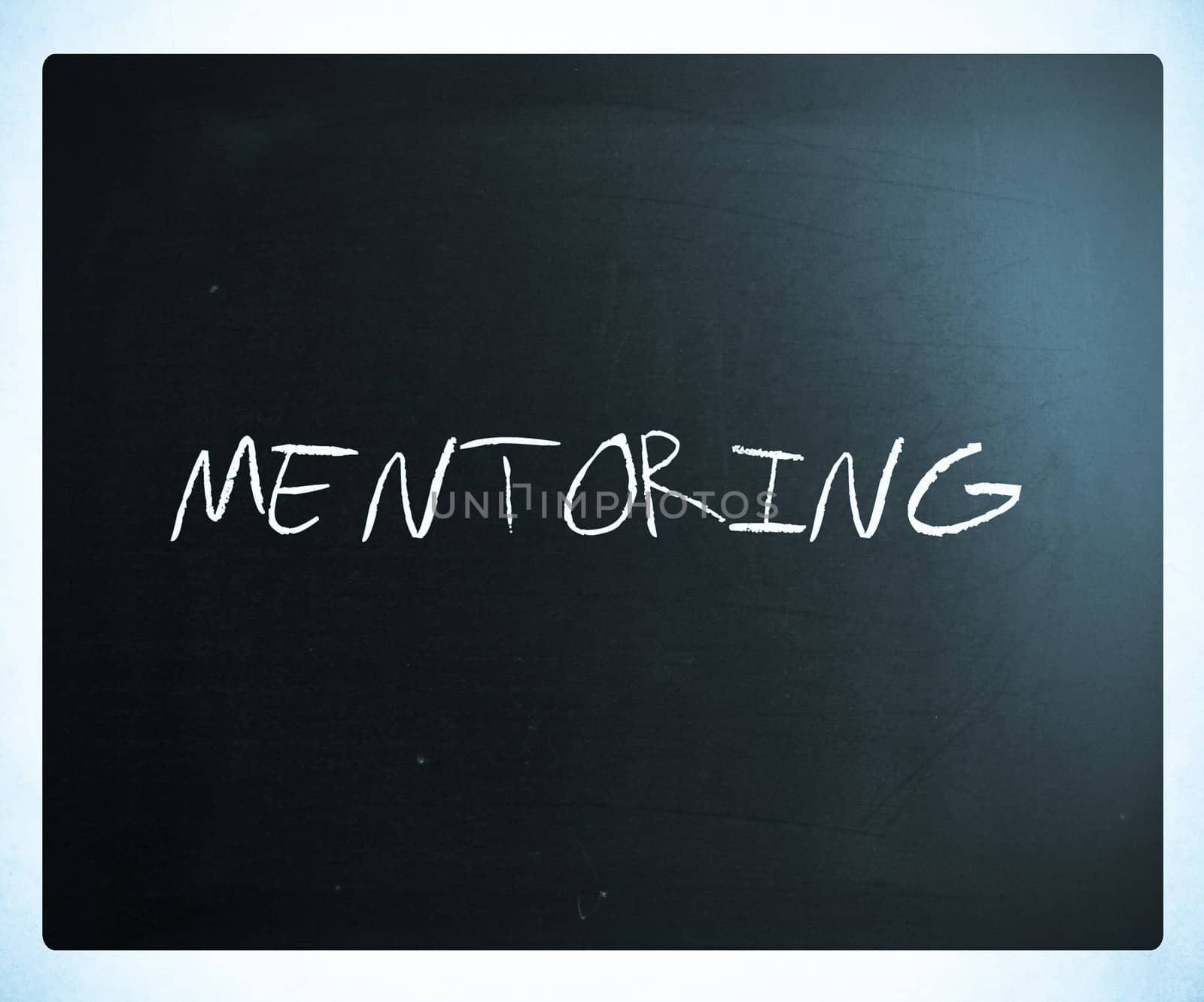 The word "Mentoring" handwritten with white chalk on a blackboard.