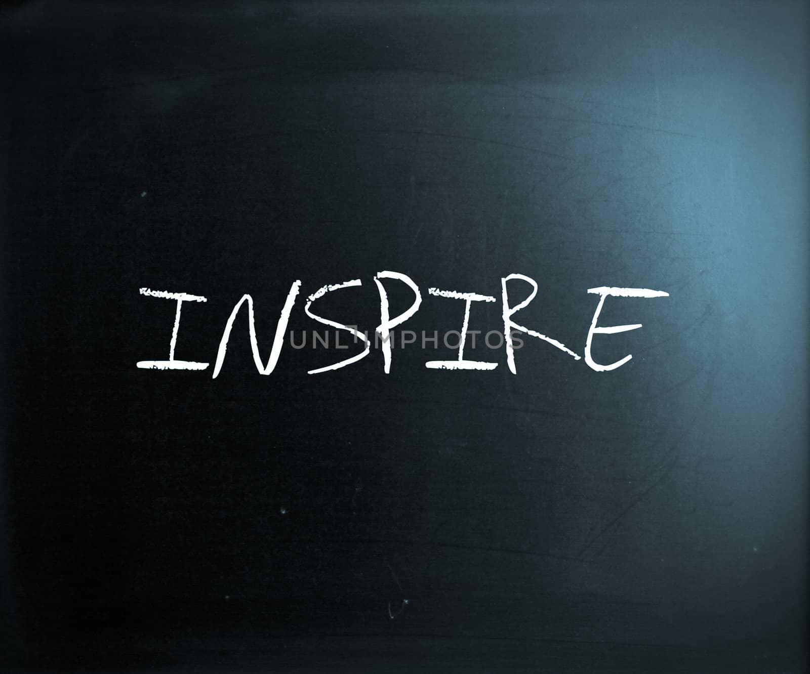 "Inspire" handwritten with white chalk on a blackboard.