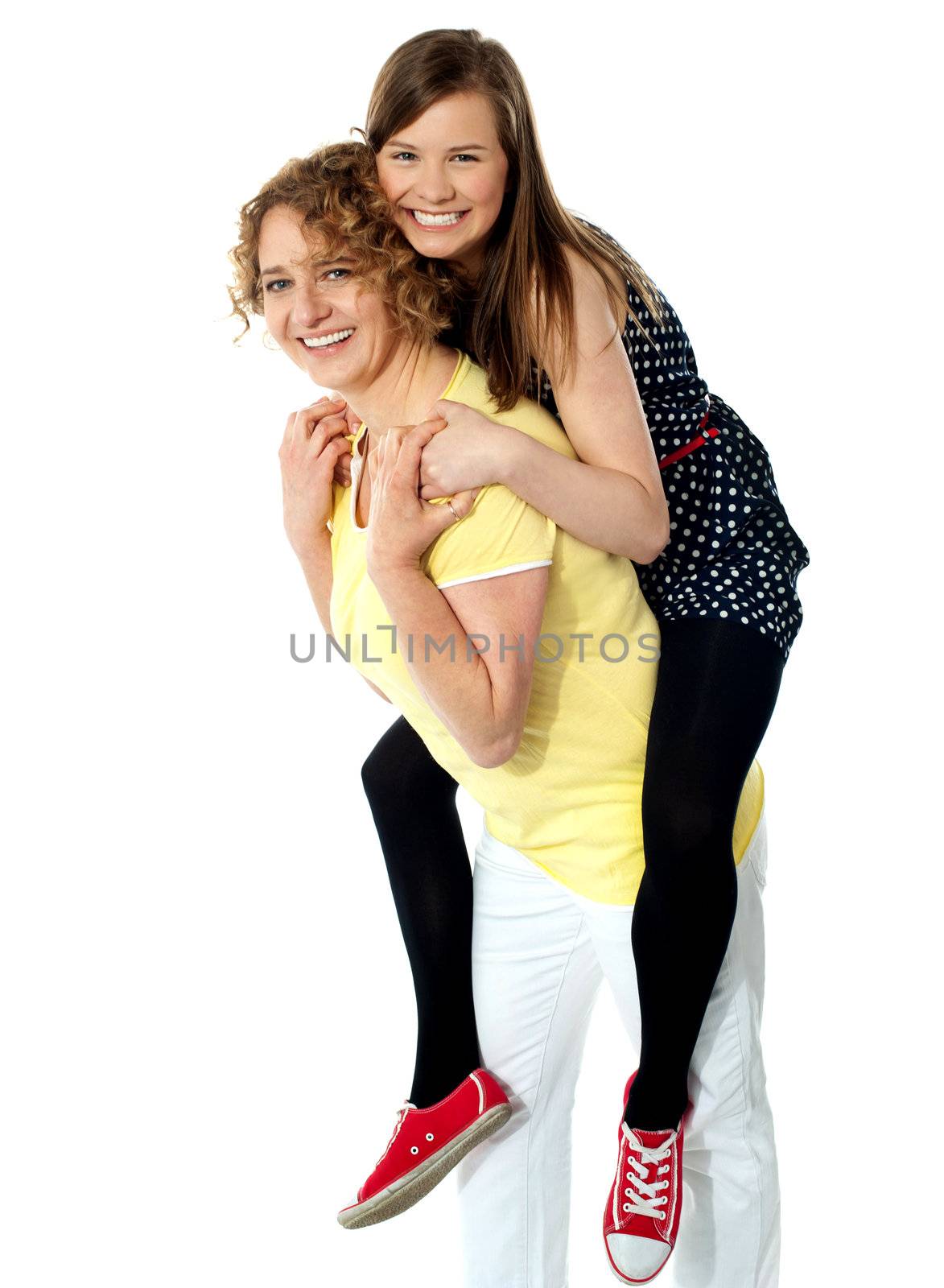 Teenage girl piggybacks her mother, studio shot