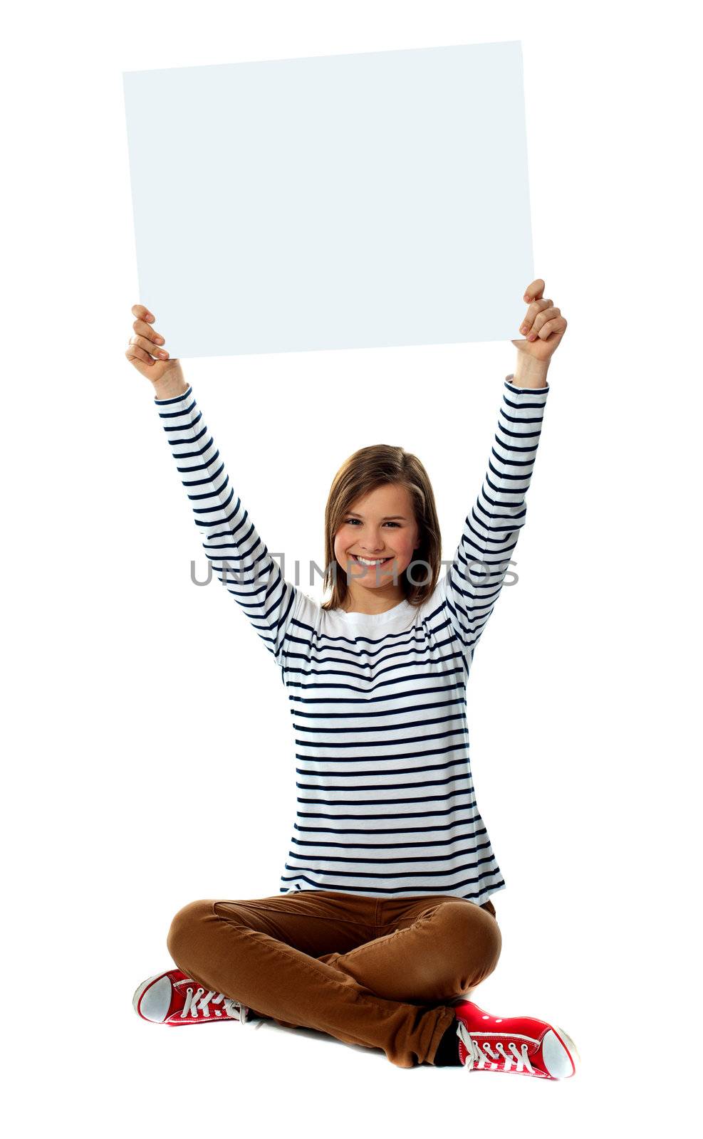 Girl holding blank billboard in upward direction. Herself seated on floor